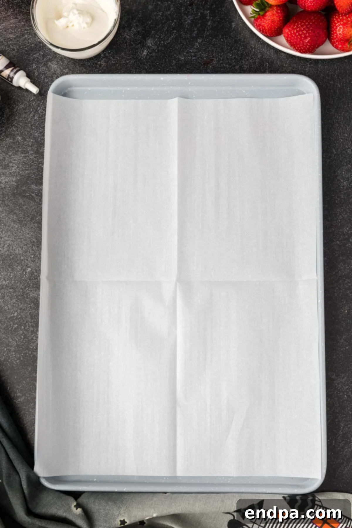 A baking sheet lined with parchment paper, prepared for placing dipped strawberries.