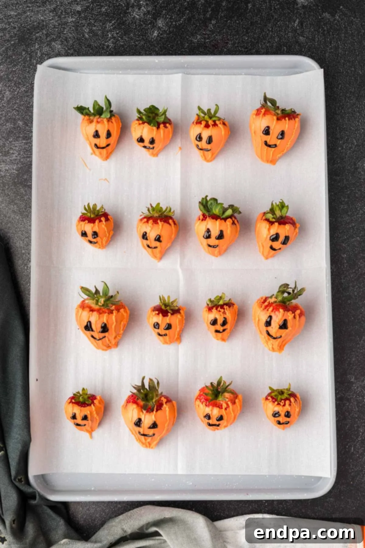 Strawberries dipped in melted orange candy wafers, ready to be decorated as pumpkins.