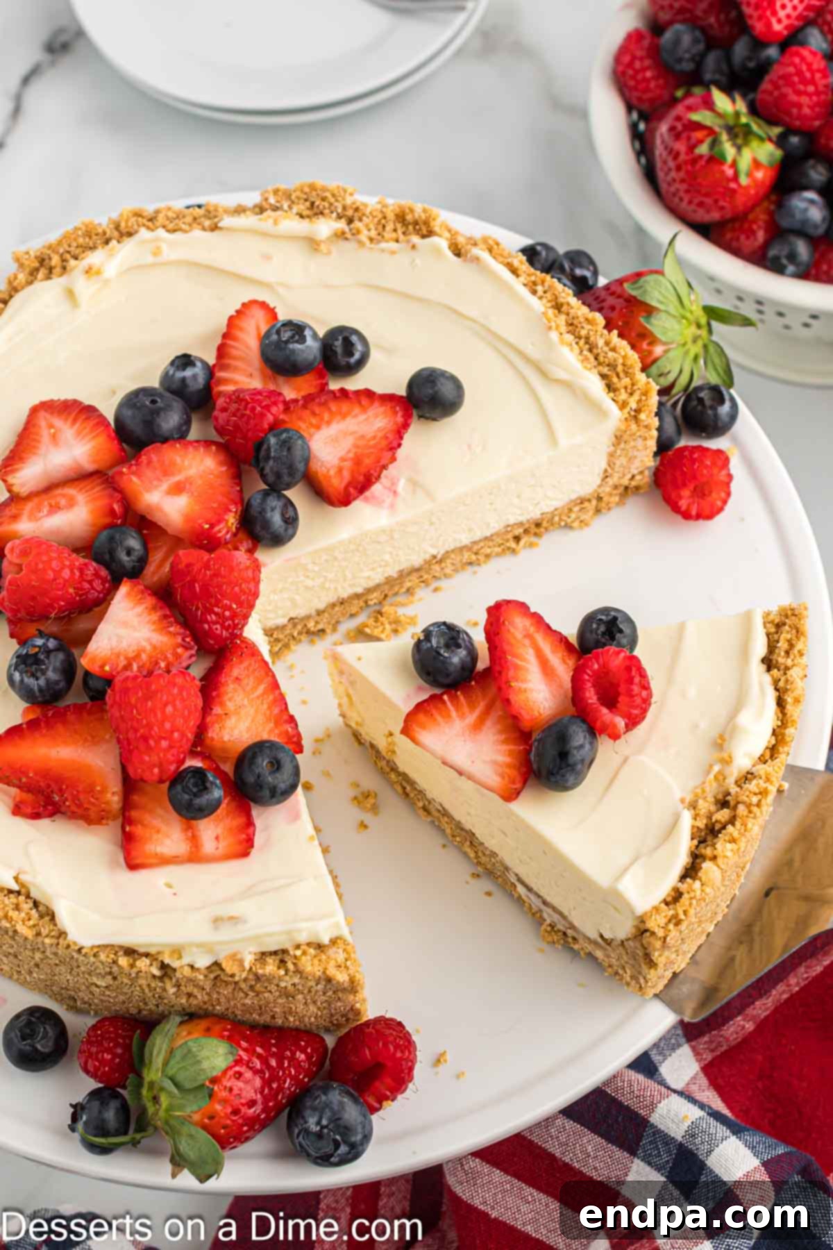 Simple No-Bake Cheesecake Dream 9 Cheesecake topped with fruit and being sliced.