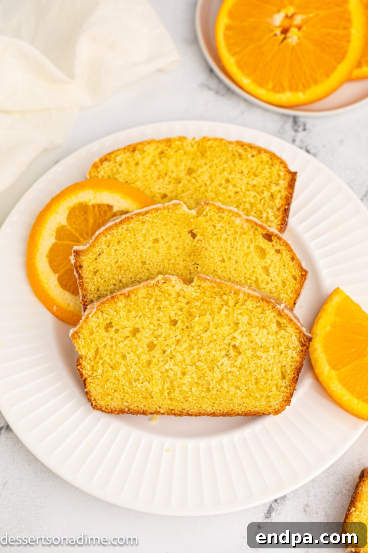 A perfectly sliced Orange Pound Cake on a white plate, showcasing its moist texture and vibrant color.