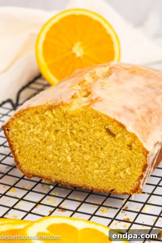 A whole orange pound cake, perfectly golden brown, cooling on a wire rack.