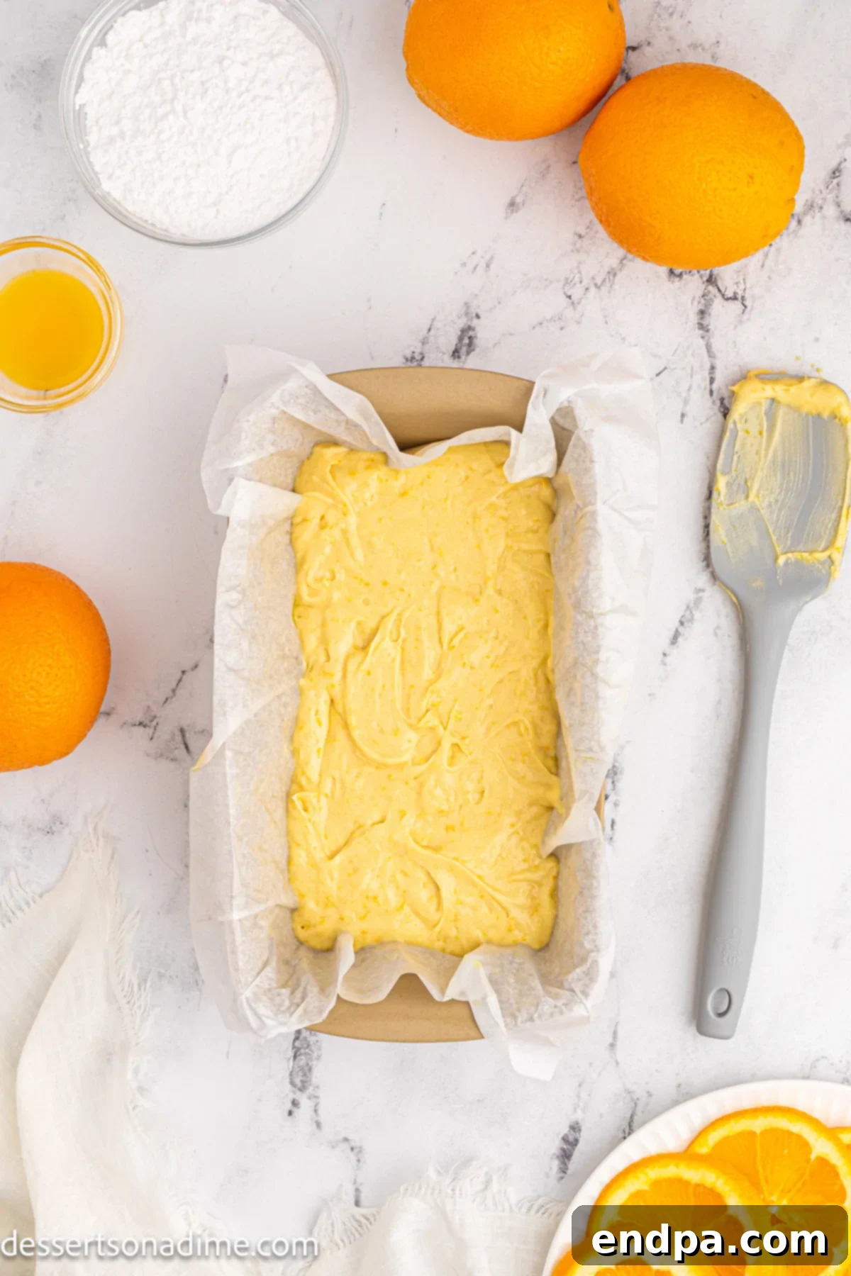 The orange pound cake batter is poured evenly into the prepared loaf pan.