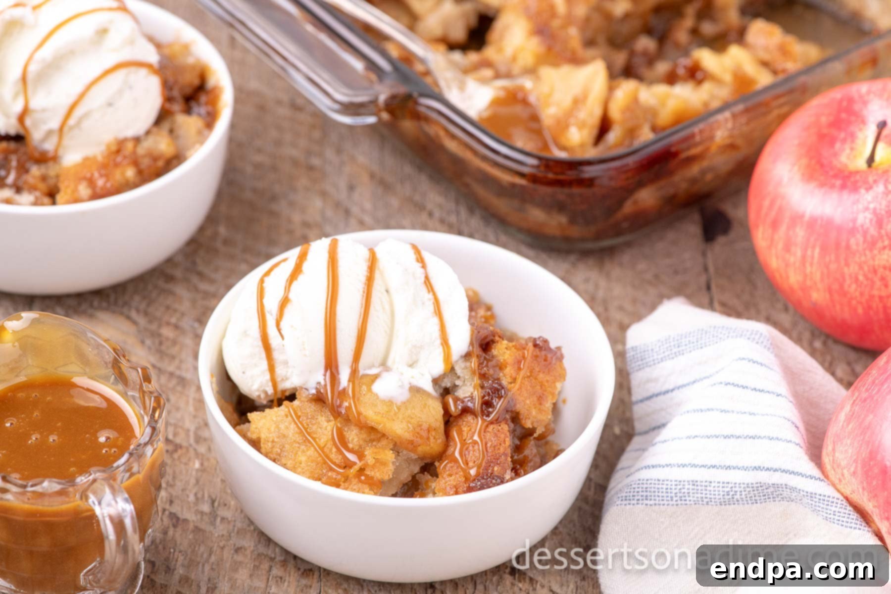 Bowl of caramel apple cobbler with vanilla ice cream and caramel drizzle.