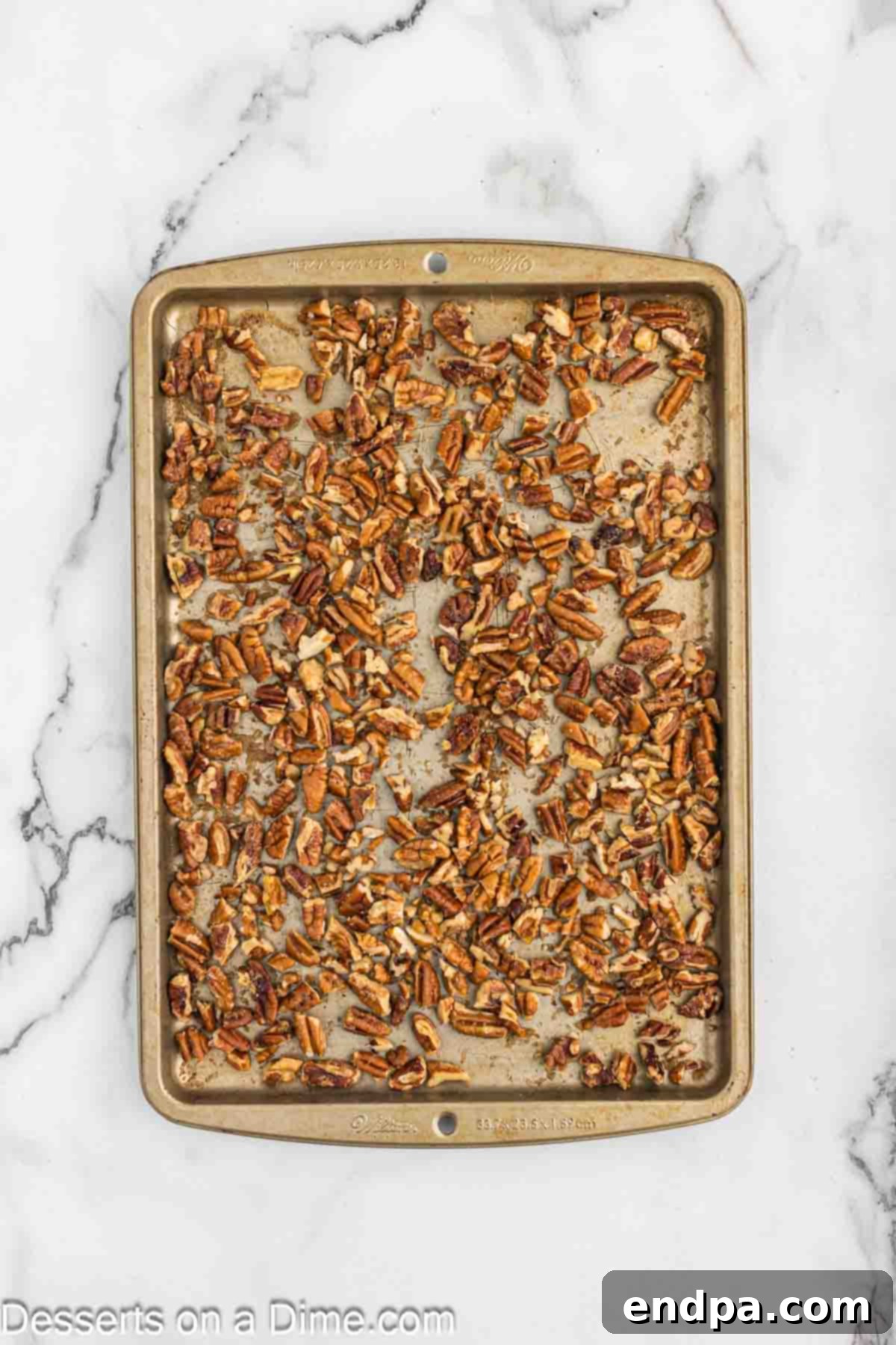 Golden Butter Pecan Cheesecake 5 Toasted pecans, evenly spread on a baking sheet, glistening with butter and brown sugar, cooling after being baked to perfection.