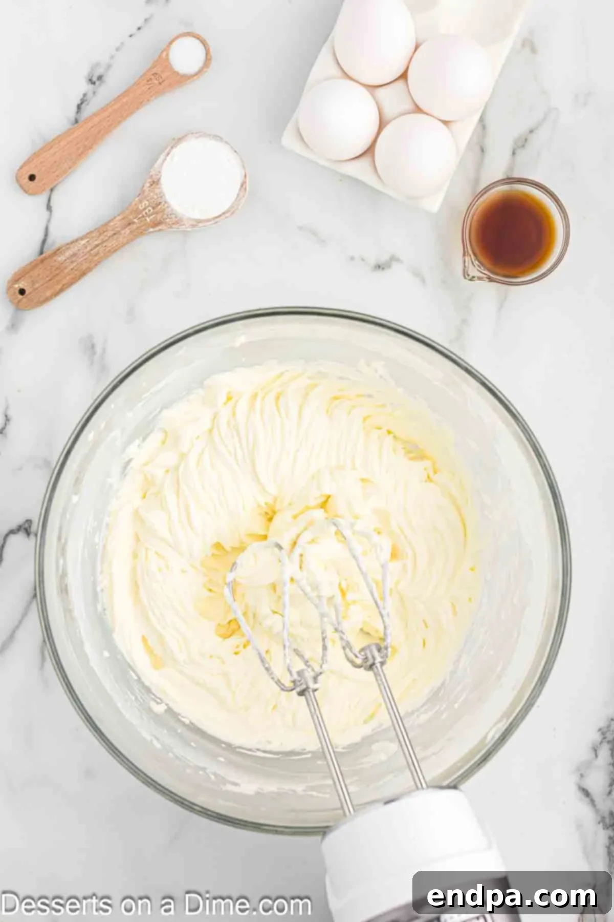 Golden Butter Pecan Cheesecake 8 Cream cheese being beaten until fluffy and smooth in a large mixing bowl with an electric mixer, forming the base of the cheesecake filling.