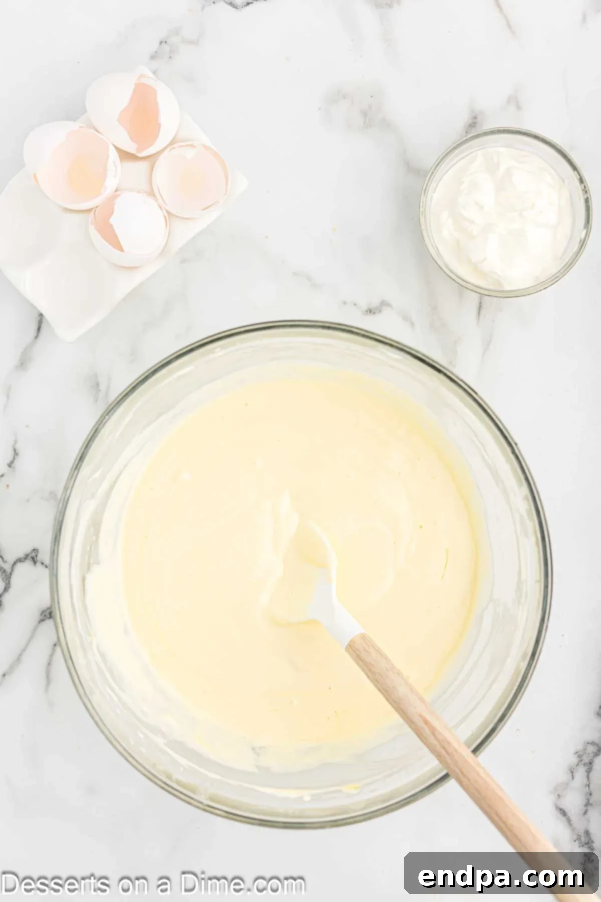 Golden Butter Pecan Cheesecake 9 Eggs being carefully added one at a time to the beaten cream cheese mixture, then gently mixed in to ensure a smooth cheesecake filling.