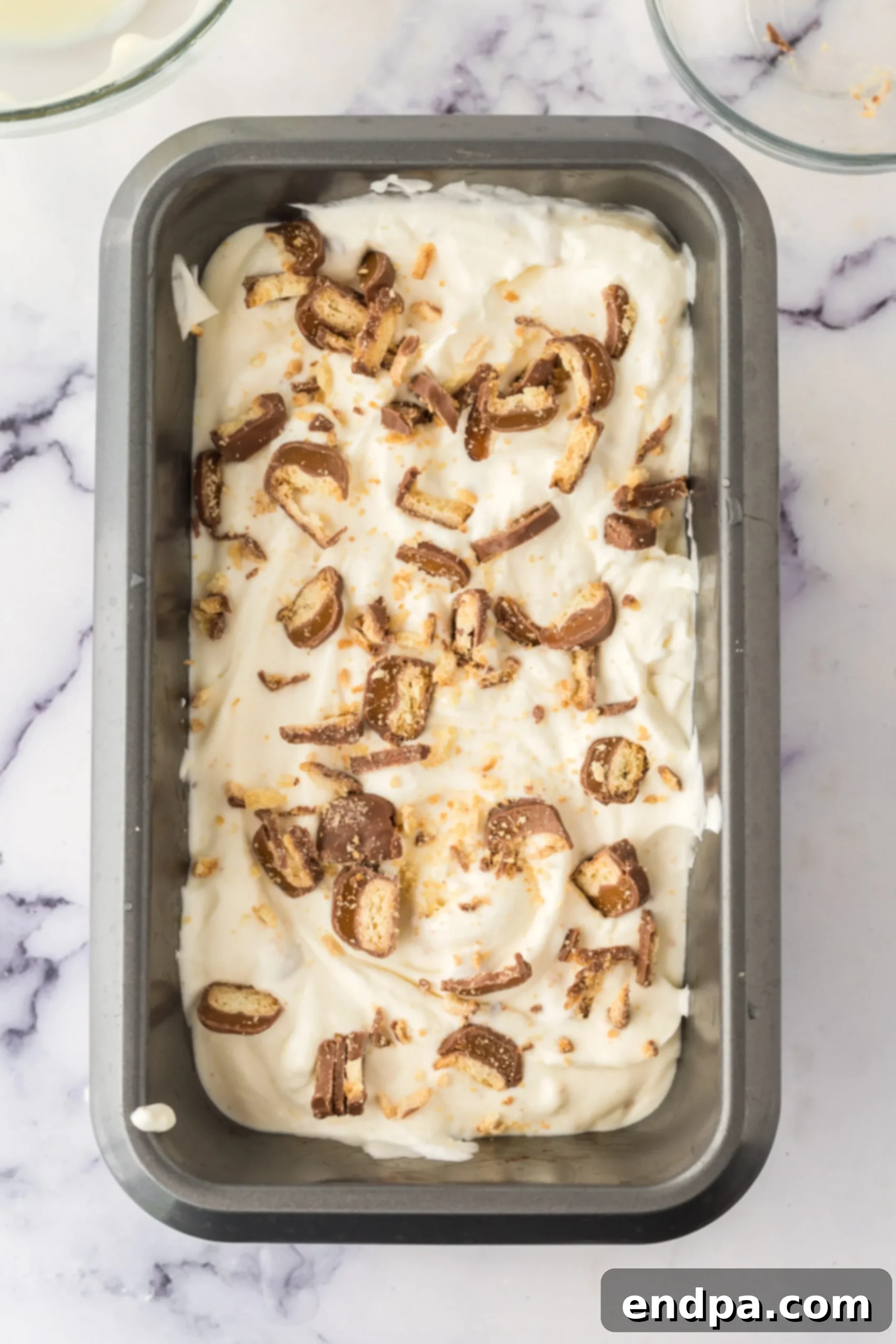 Spreading the Twix ice cream mixture into a loaf pan.