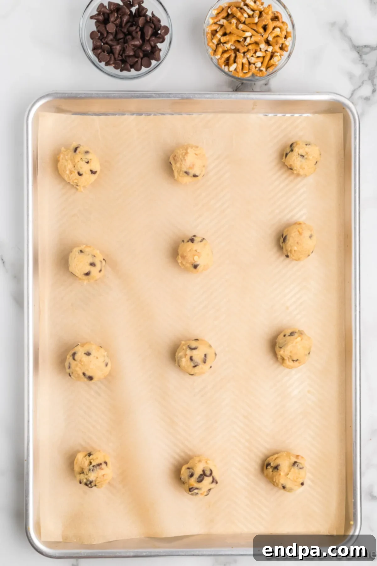 Uniform balls of cookie dough arranged on a parchment-lined baking sheet.