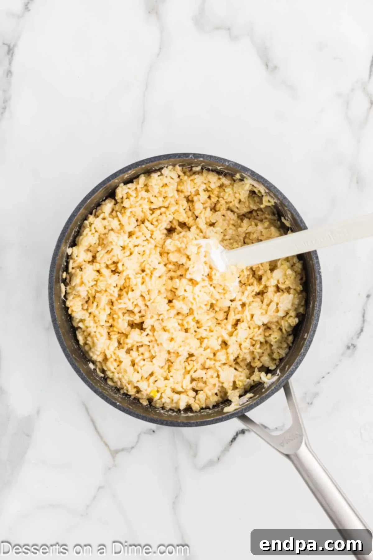 Rice Krispies cereal combined with the marshmallow mixture in a pan, being stirred.