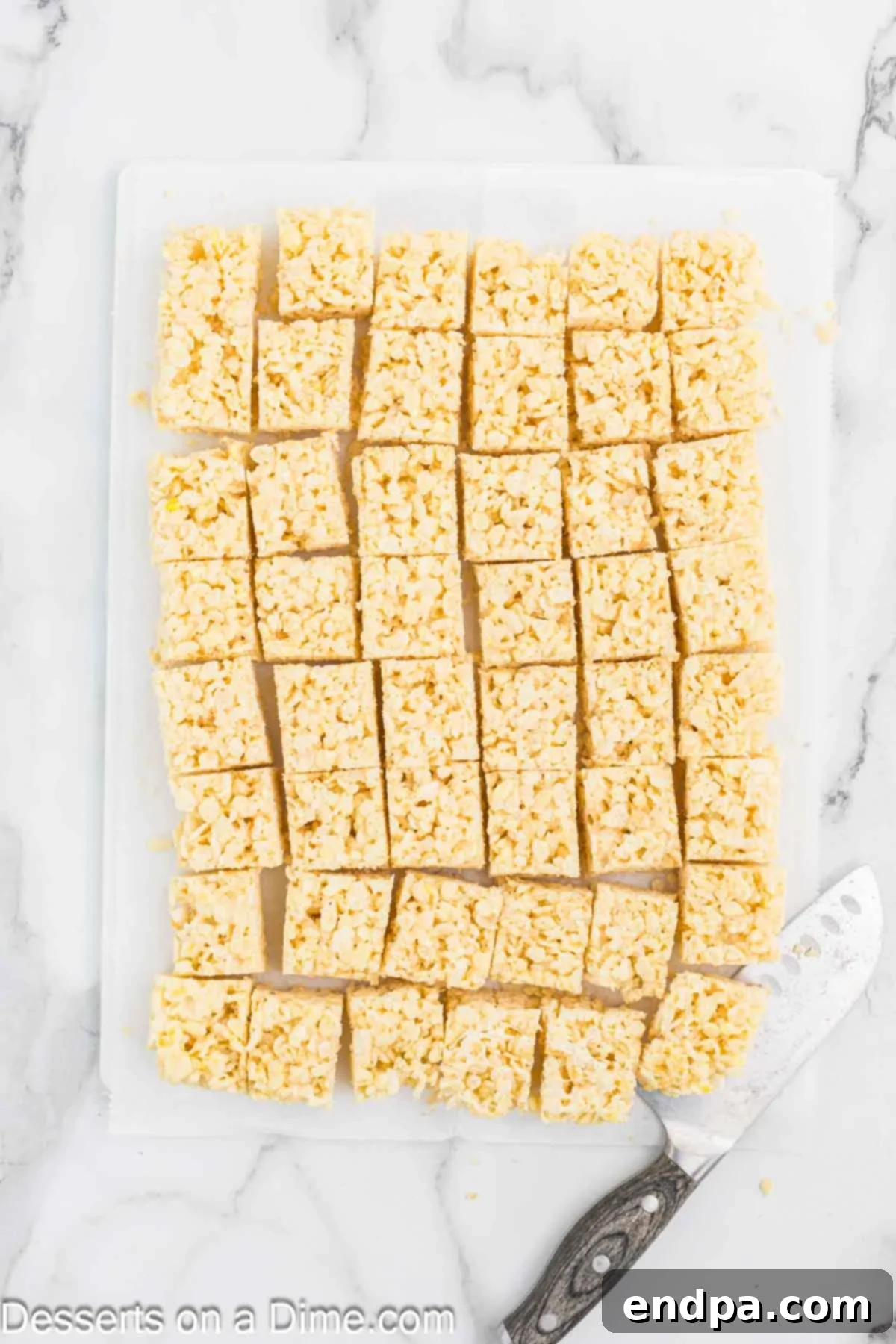 The cooled Rice Krispie treat slab cut into uniform squares on a cutting board.