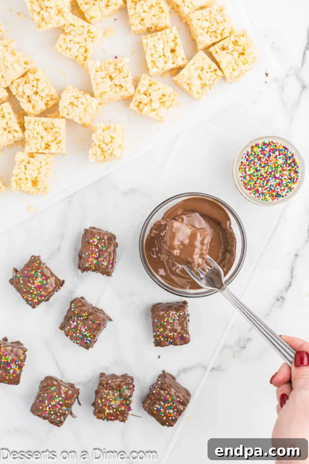 A bowl of melted chocolate with Rice Krispie treat bars being dipped into it.