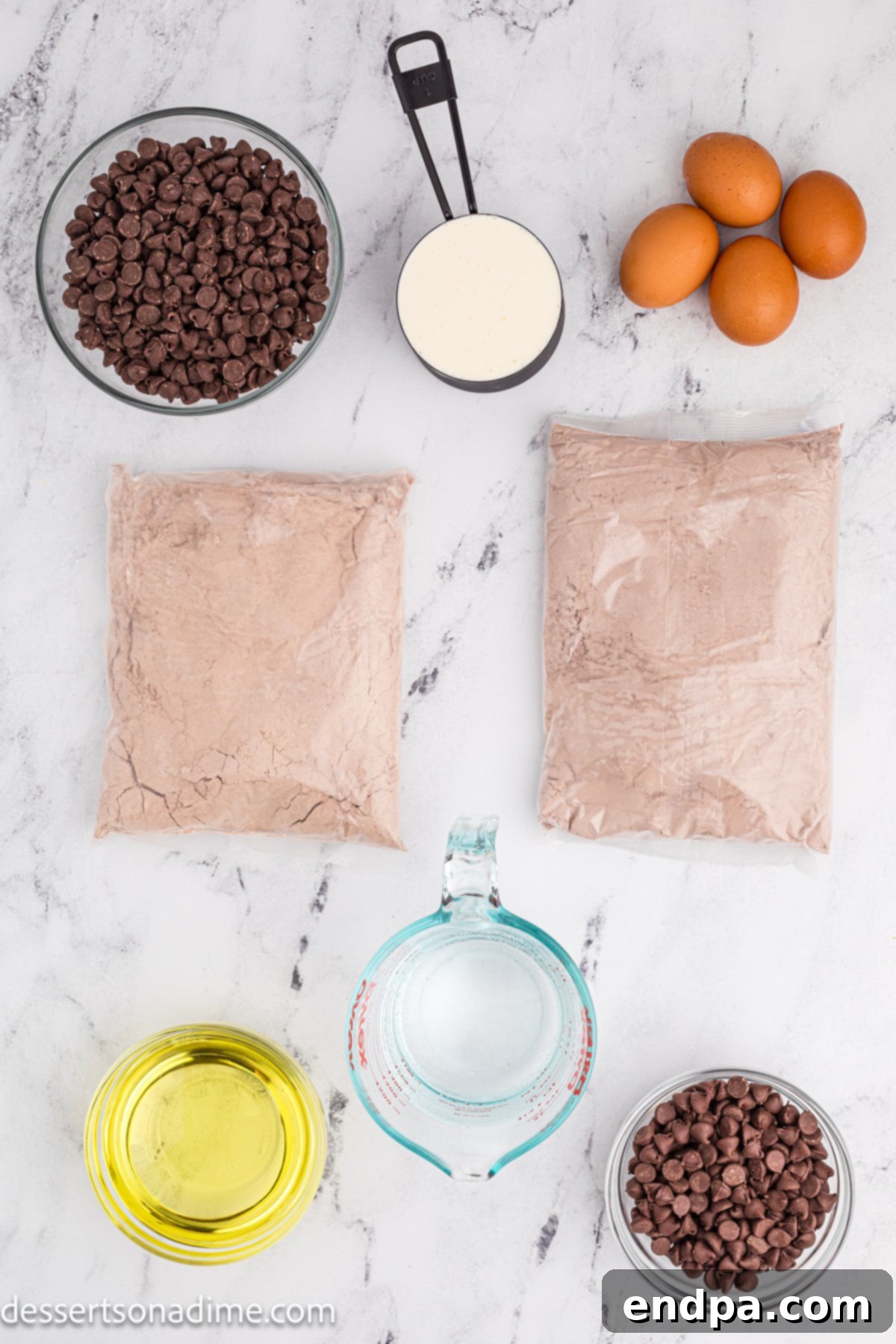 A flat lay of ingredients for Chocolate Brownie Cake, including chocolate cake mix, fudge brownie mix, eggs, and chocolate chips.