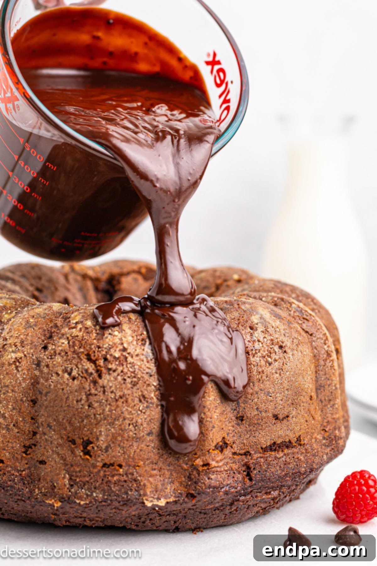 Glossy chocolate ganache being poured over a fully cooled Chocolate Brownie Cake.