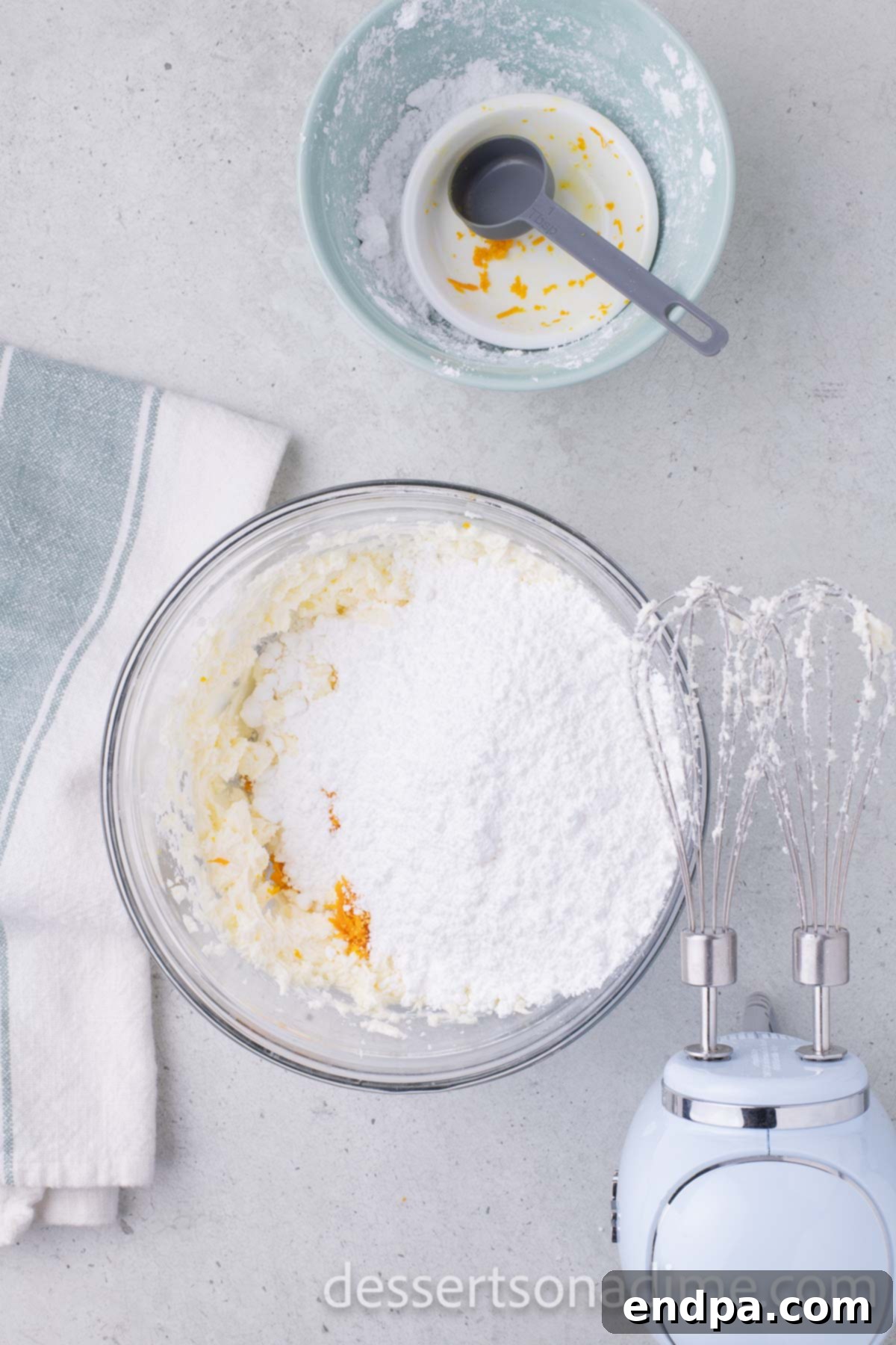 Orange Burst Brownies 11 Powdered sugar added to frosting mixture in bowl.
