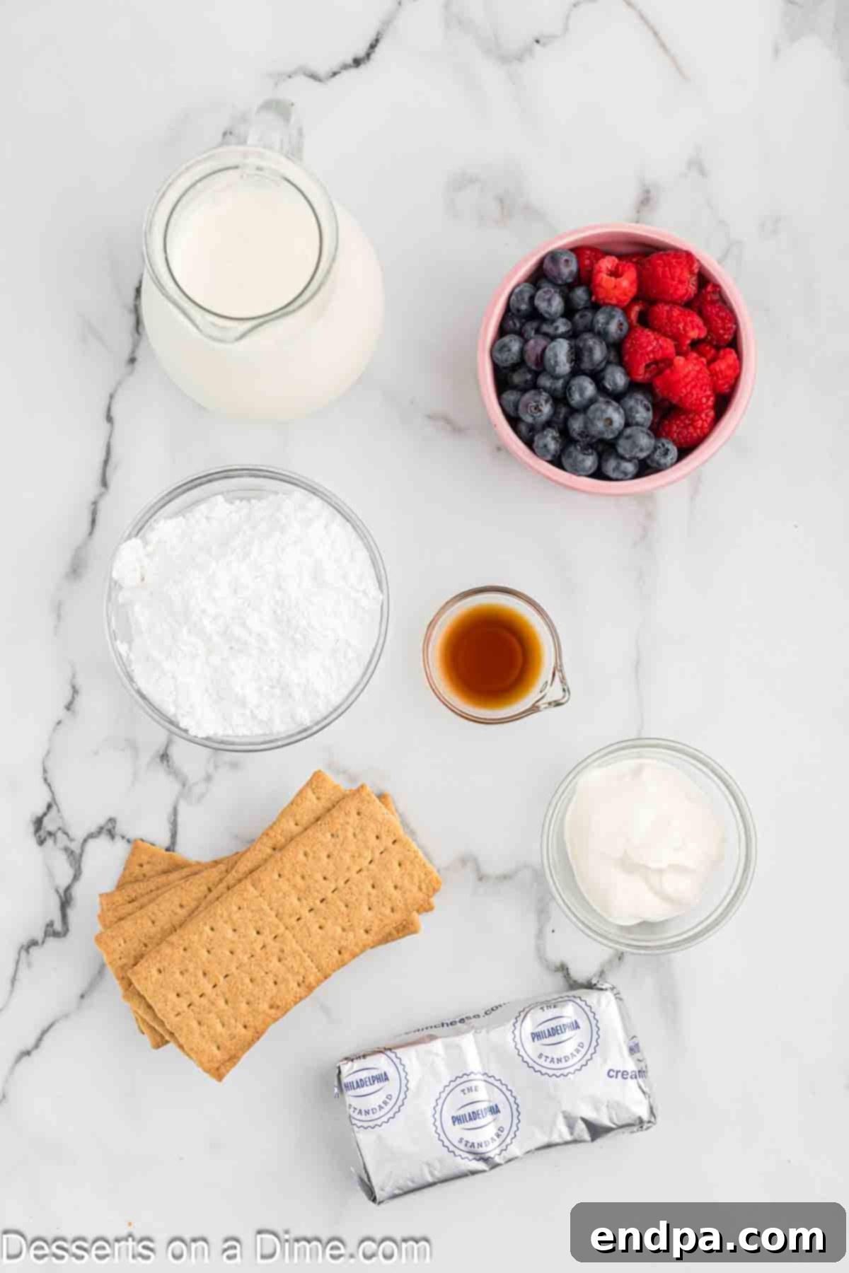 A selection of ingredients for cheesecake mousse including heavy whipping cream, cream cheese, sour cream, powdered sugar, vanilla extract, graham crackers, and fresh berries.