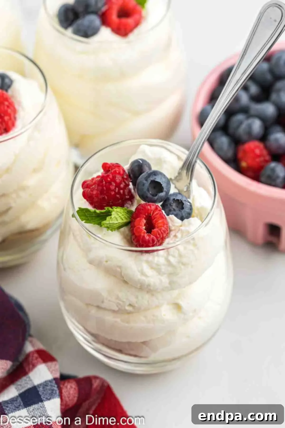 Another view of cheesecake mousse in a glass, generously topped with fresh blueberries and raspberries.