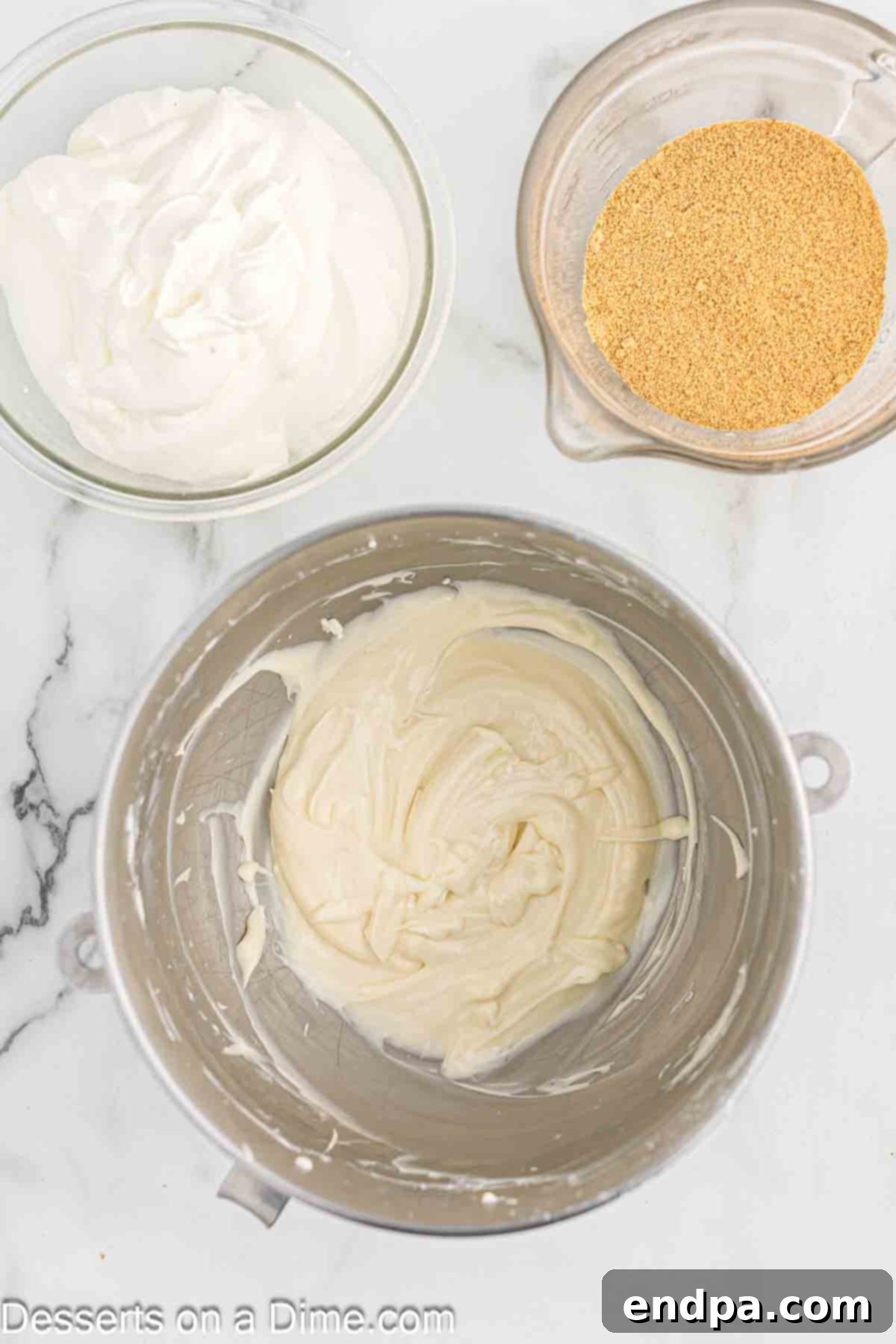Softened cream cheese and sour cream are combined in a mixing bowl with a paddle attachment.