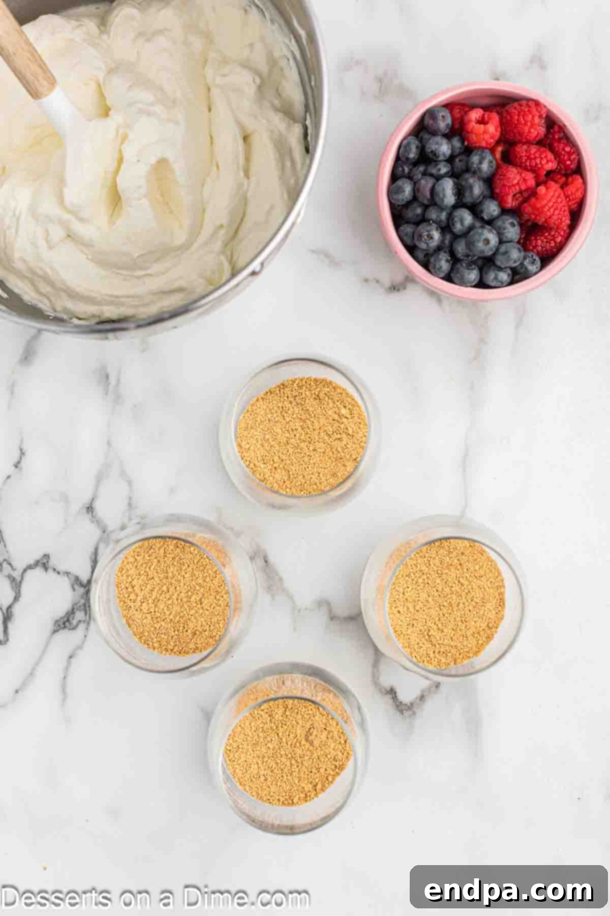 Crushed graham cracker crumbs are poured into the bottom of clear serving glasses.