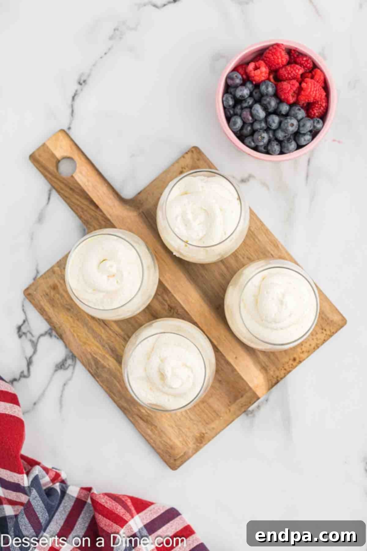 The cheesecake mousse mixture is spooned or piped over the graham cracker crumbs in each serving cup.