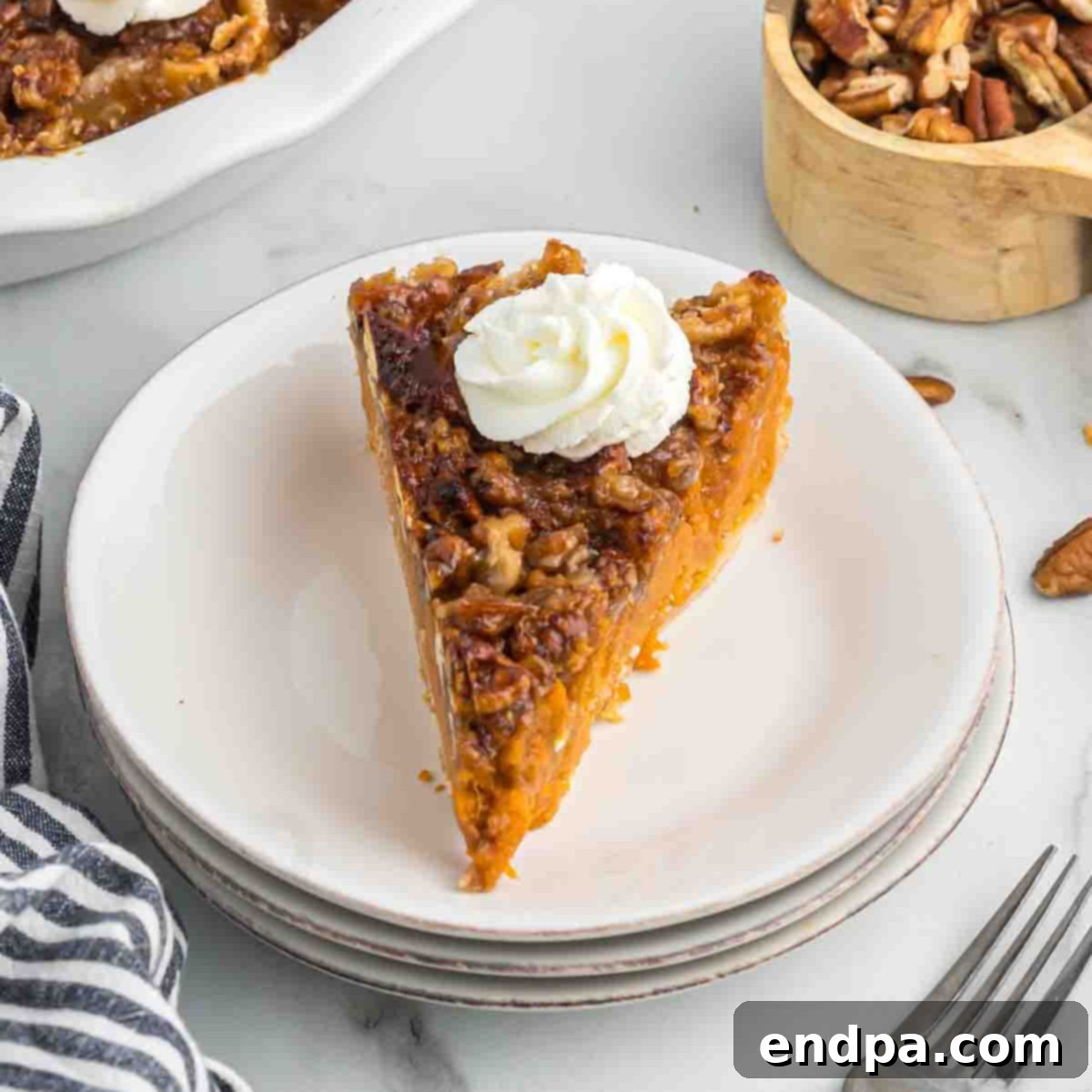 Velvety Sweet Potato Pecan Delight 7 Pie sliced and topped with cool whip on a plate, ready to be served.