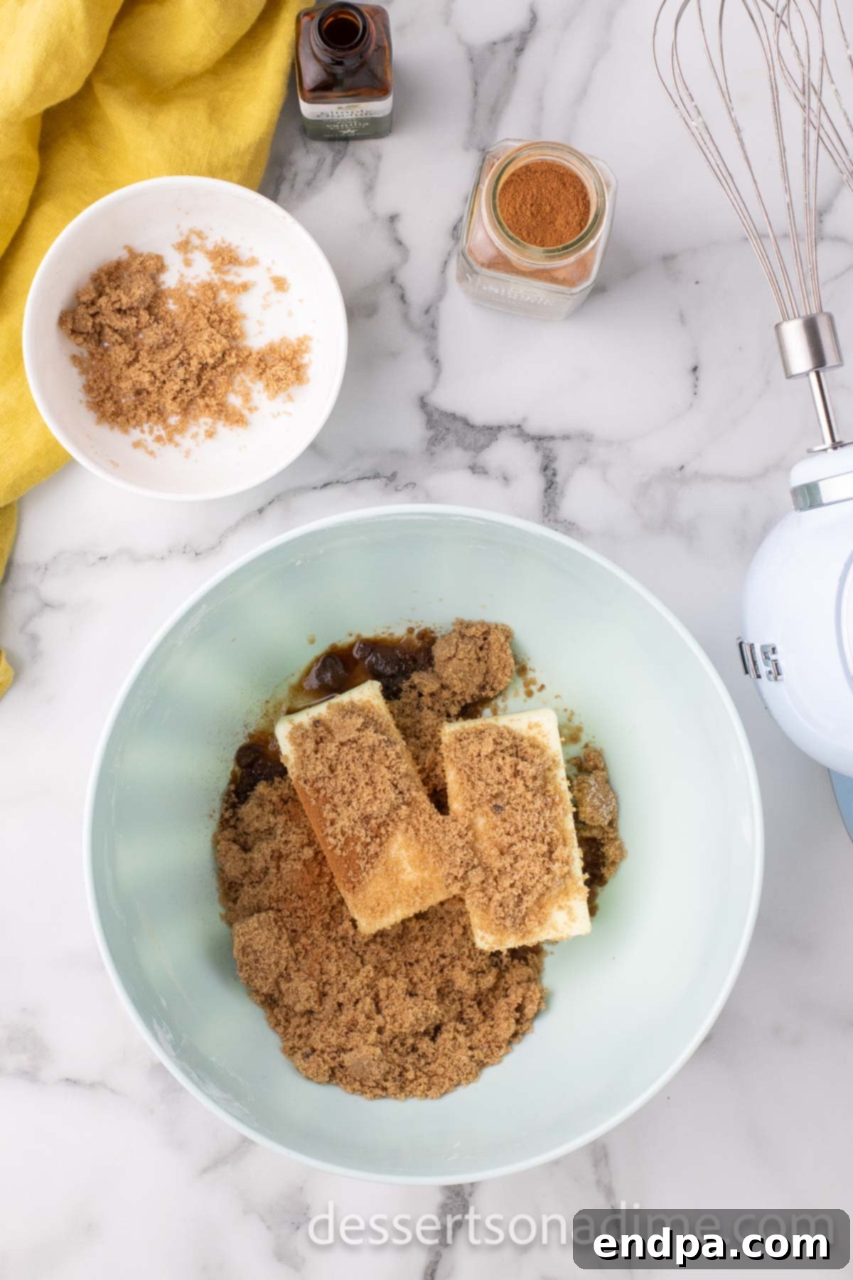 A mixing bowl containing softened butter, brown sugar, and vanilla extract, combined for the cinnamon buttercream frosting.
