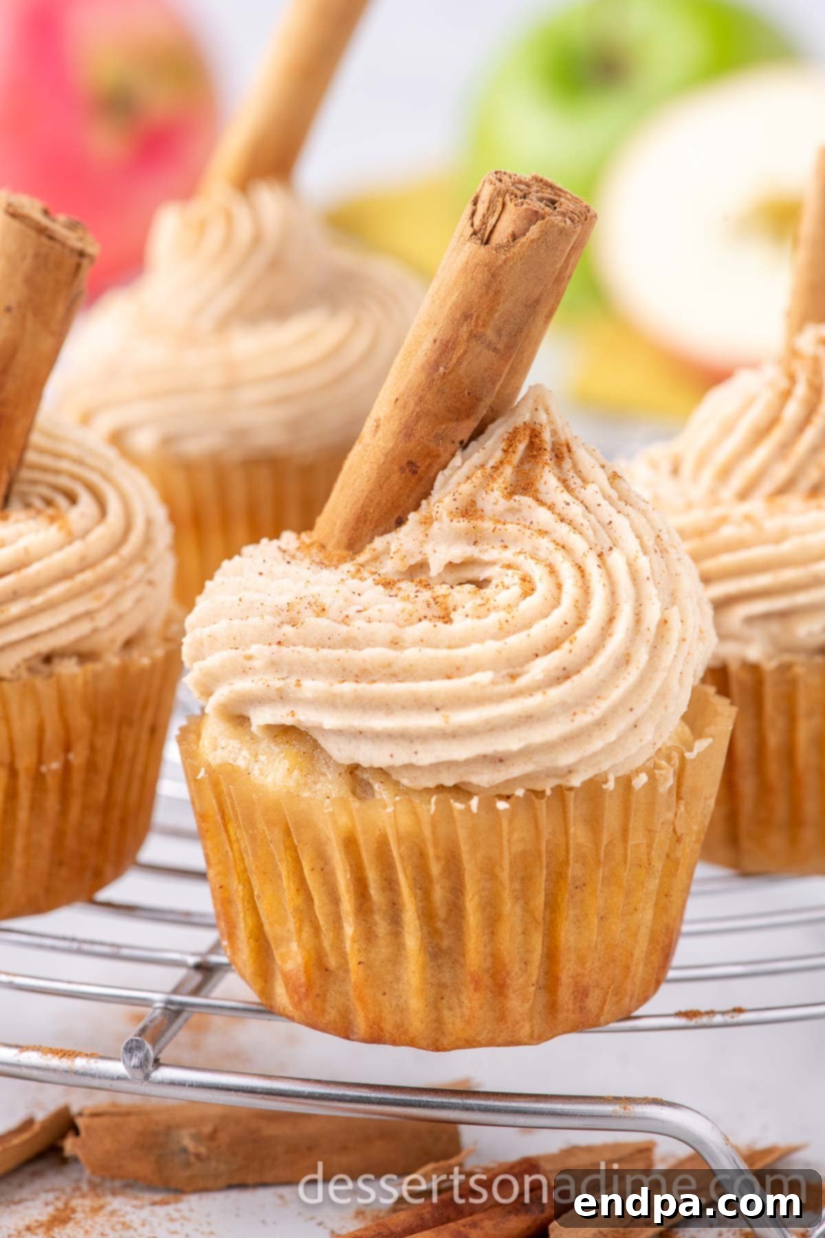 A perfectly baked and frosted apple cider cupcake, presented beautifully on a wire rack.