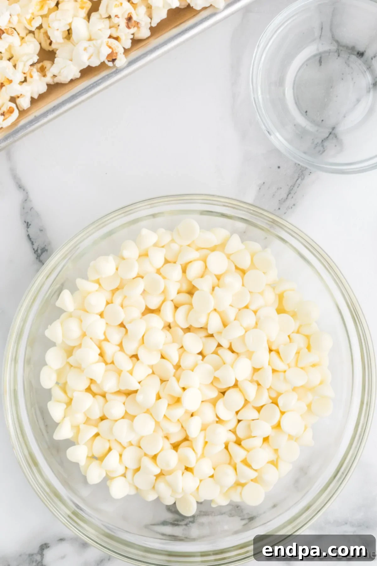 A small, microwave-safe bowl filled with white chocolate chips, ready to be melted with a touch of vegetable oil.
