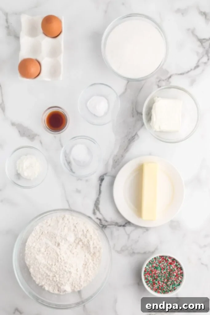 Arrangement of Christmas sprinkle cookie ingredients: granulated sugar, softened butter, cream cheese, vanilla extract, all-purpose flour, and colorful nonpareil sprinkles.