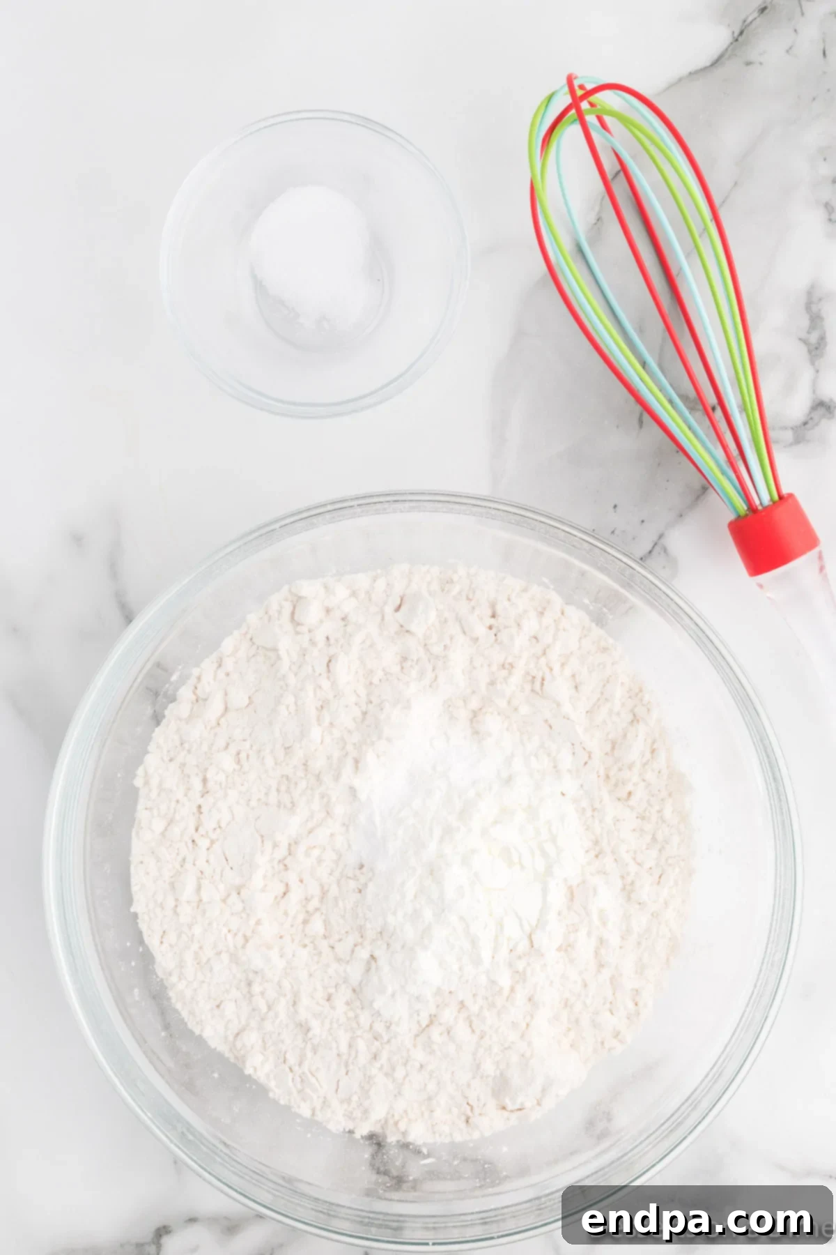 Dry ingredients (flour, cornstarch, baking soda, salt) expertly whisked together in a large mixing bowl.