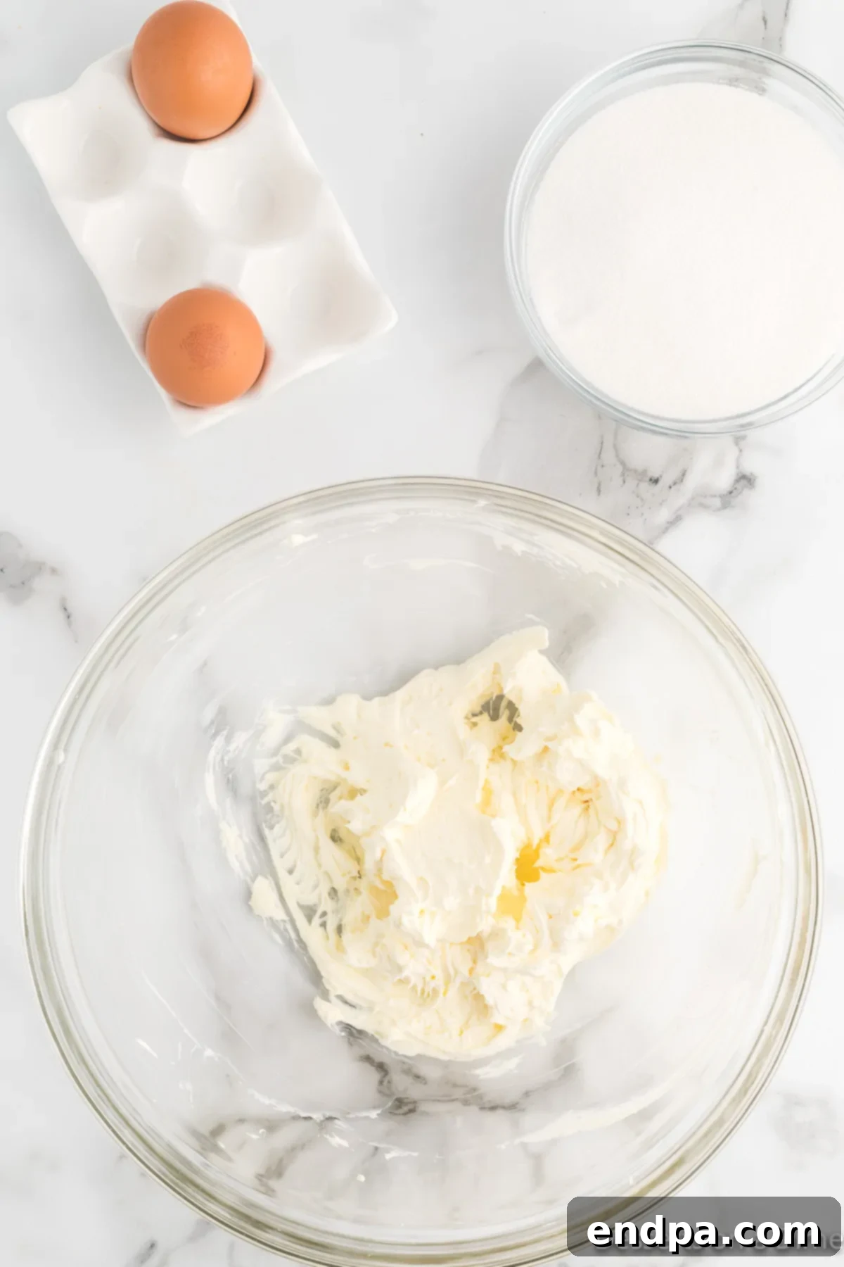 Softened butter, cream cheese, and granulated sugar being creamed together in a stand mixer bowl using a paddle attachment until light and fluffy.