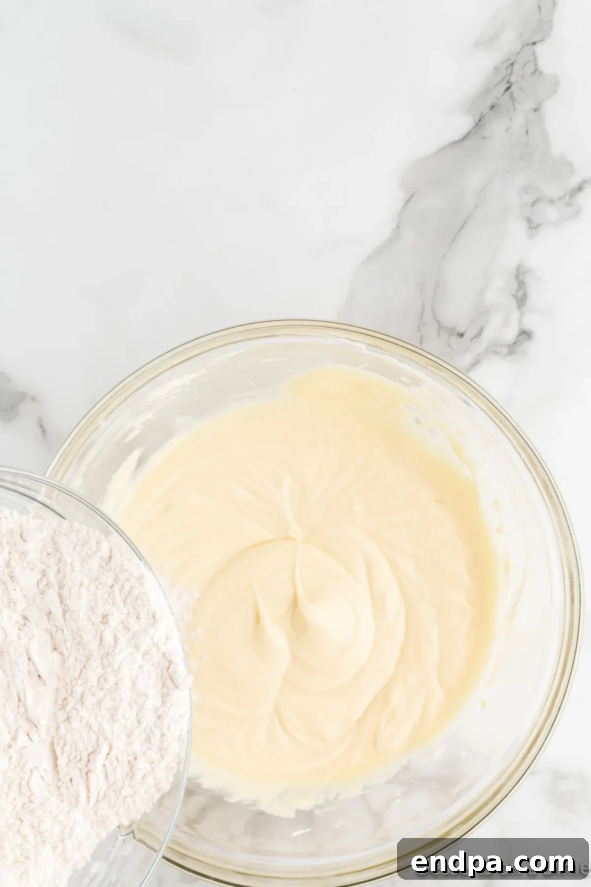 Gradually adding the previously prepared dry ingredients to the creamed wet mixture in a stand mixer, mixing until just combined.
