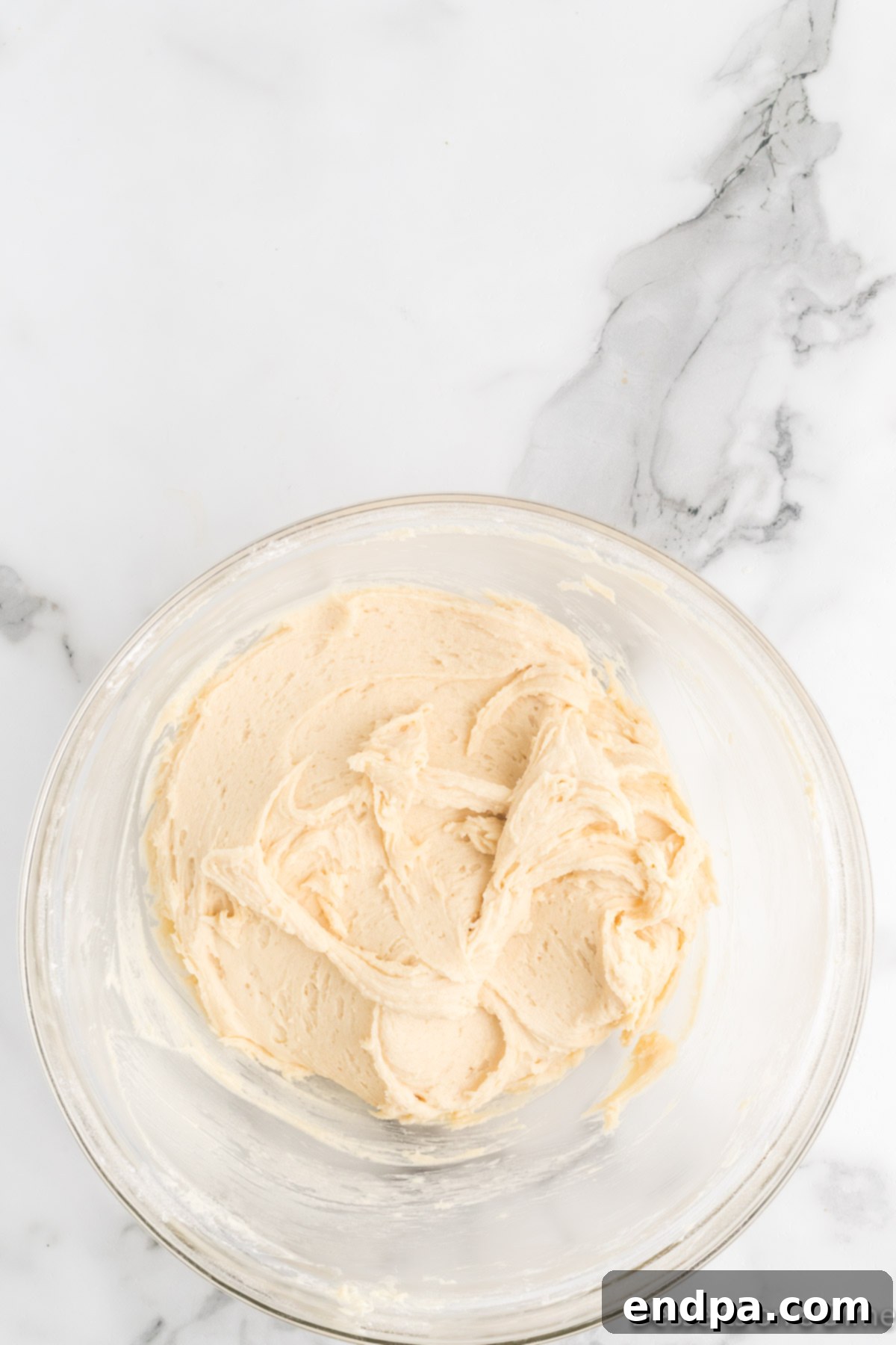 Cookie dough covered tightly with plastic wrap in a bowl, placed in the refrigerator for chilling.