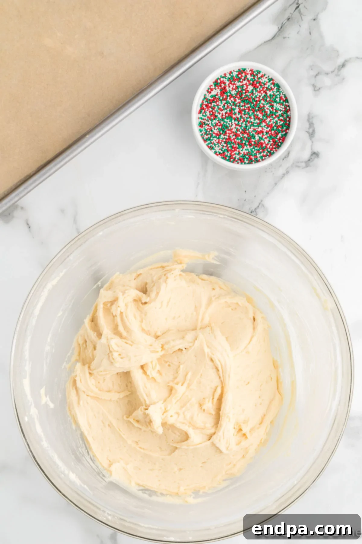 A shallow bowl filled with an abundance of red, green, and white festive sprinkles, perfectly prepared for coating cookie dough.