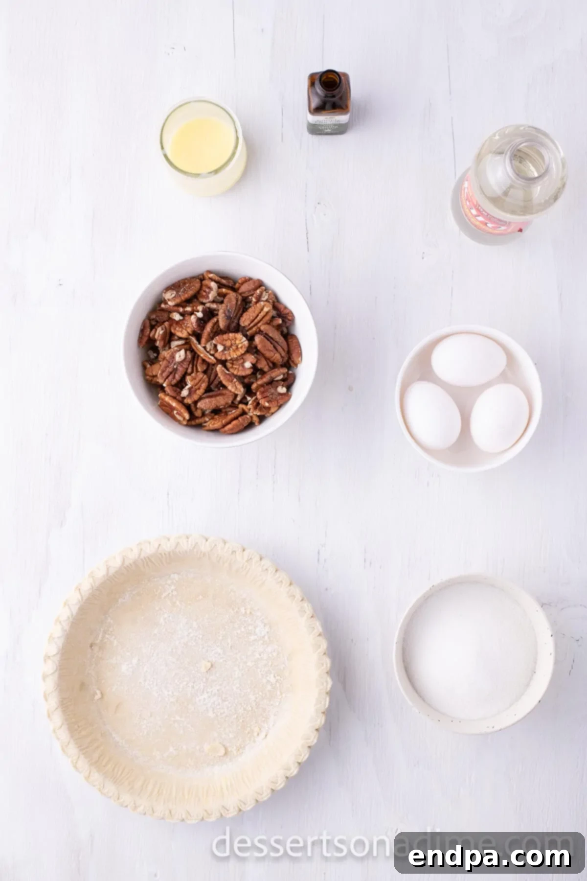 Perfect Karo Syrup Pecan Pie 3 A flat lay of ingredients for a classic pecan pie recipe, including corn syrup, fresh eggs, butter, vanilla extract, a generous pile of pecan halves, and an unbaked pie crust.