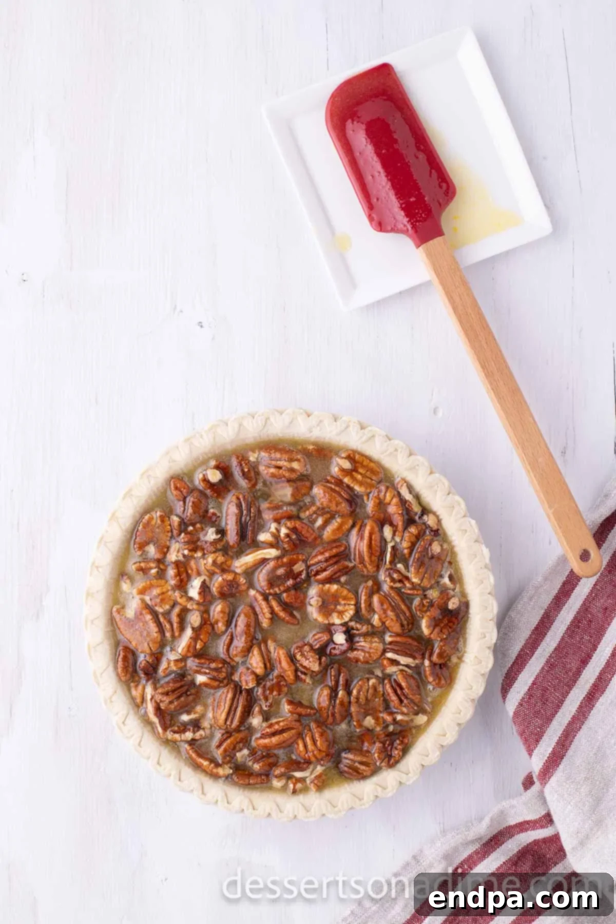 Perfect Karo Syrup Pecan Pie 5 The pecan pie filling, a glossy mixture of corn syrup and pecans, being carefully poured into an unbaked pie crust in a deep dish pan.