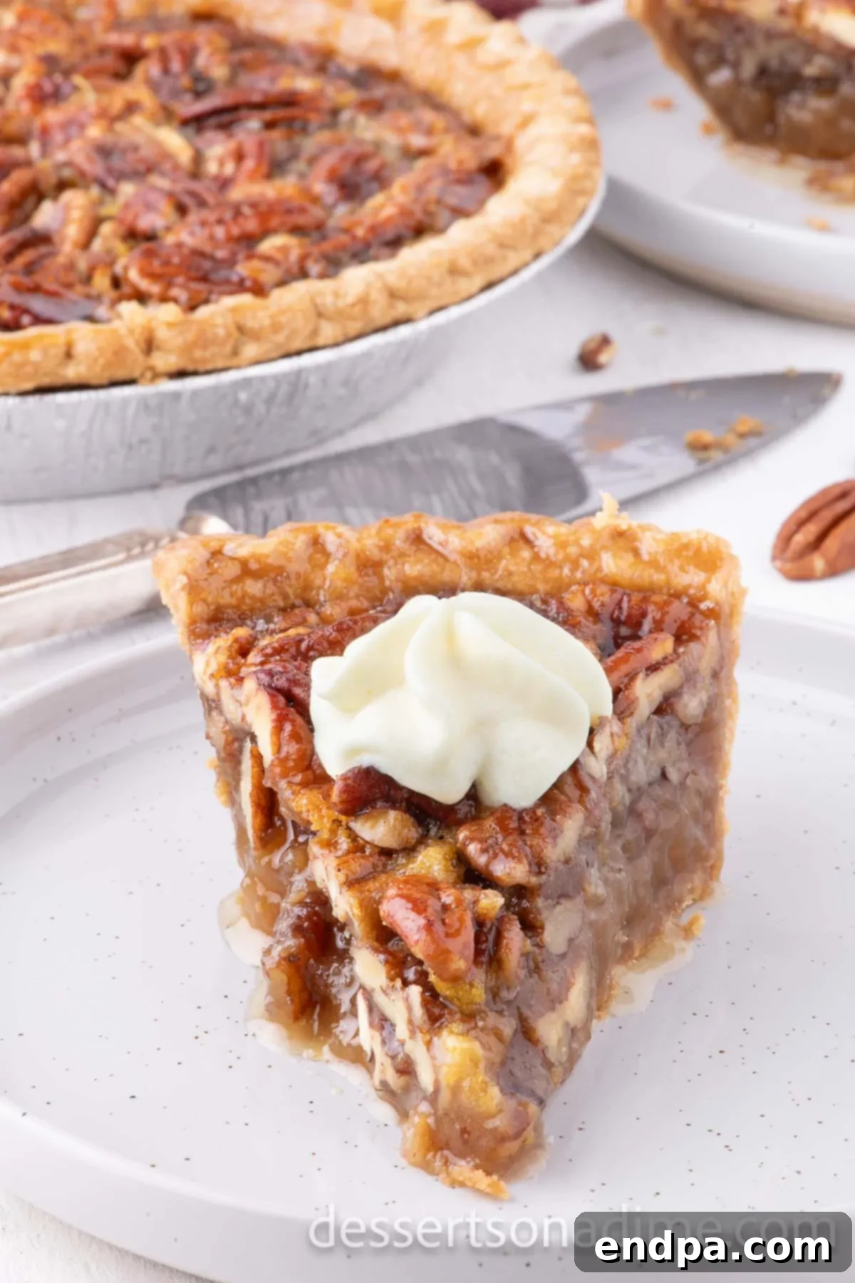 Perfect Karo Syrup Pecan Pie 7 A tempting slice of pecan pie garnished with a generous dollop of whipped cream, inviting you to enjoy this delicious homemade dessert.