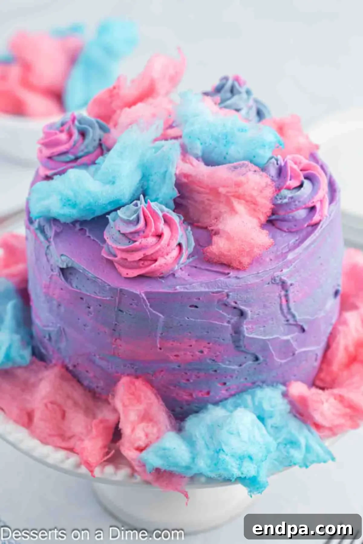 Close up image of cotton candy cake decorated on a cake stand, showcasing its vibrant layers and fluffy topping.
