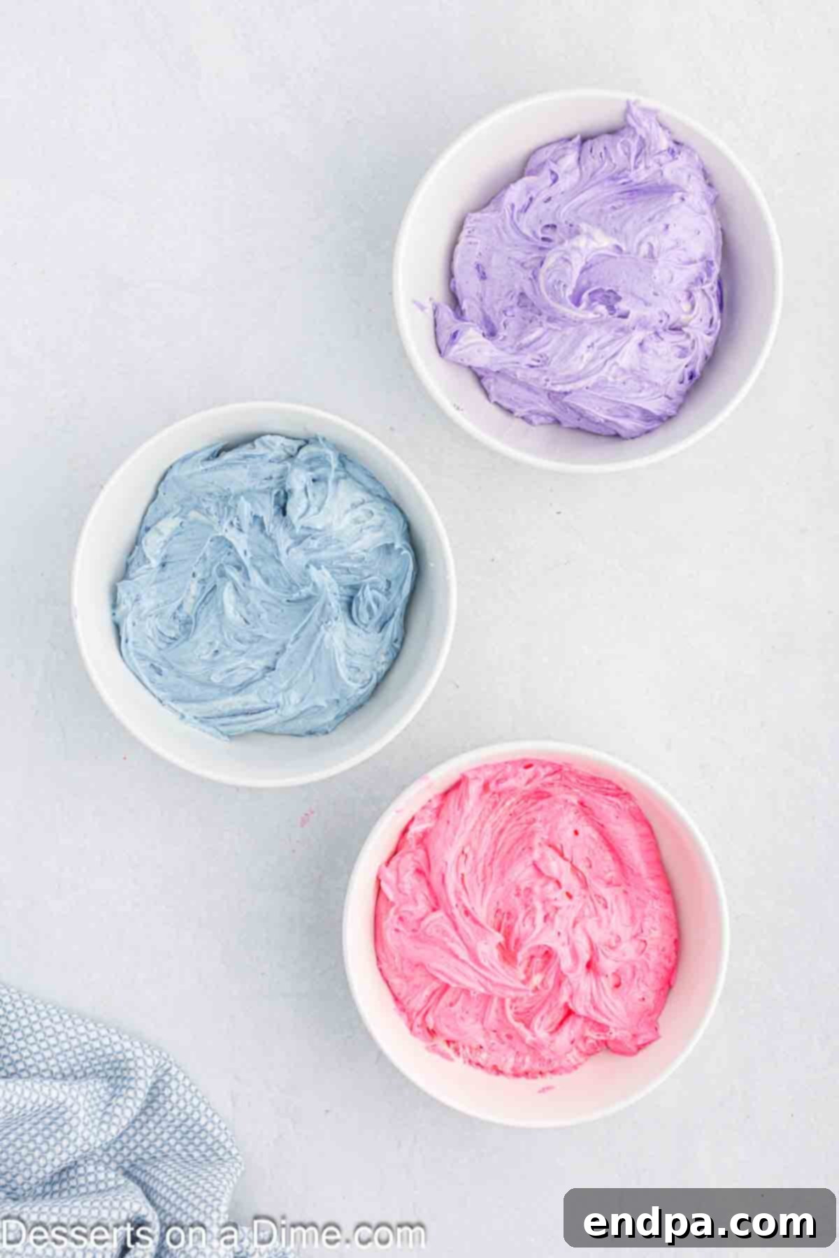 Buttercream frosting divided into three bowls with different food coloring added.