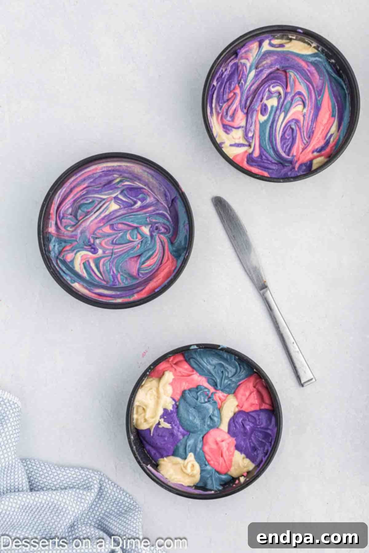 Colored and uncolored batter spooned randomly into each cake pan.