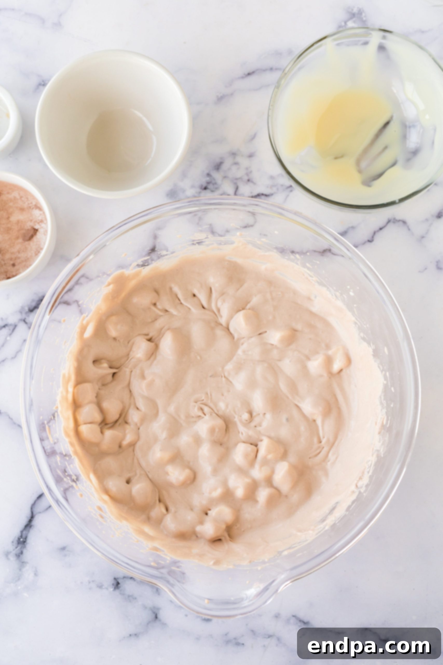 Sweetened condensed milk and marshmallows combined in bowl.