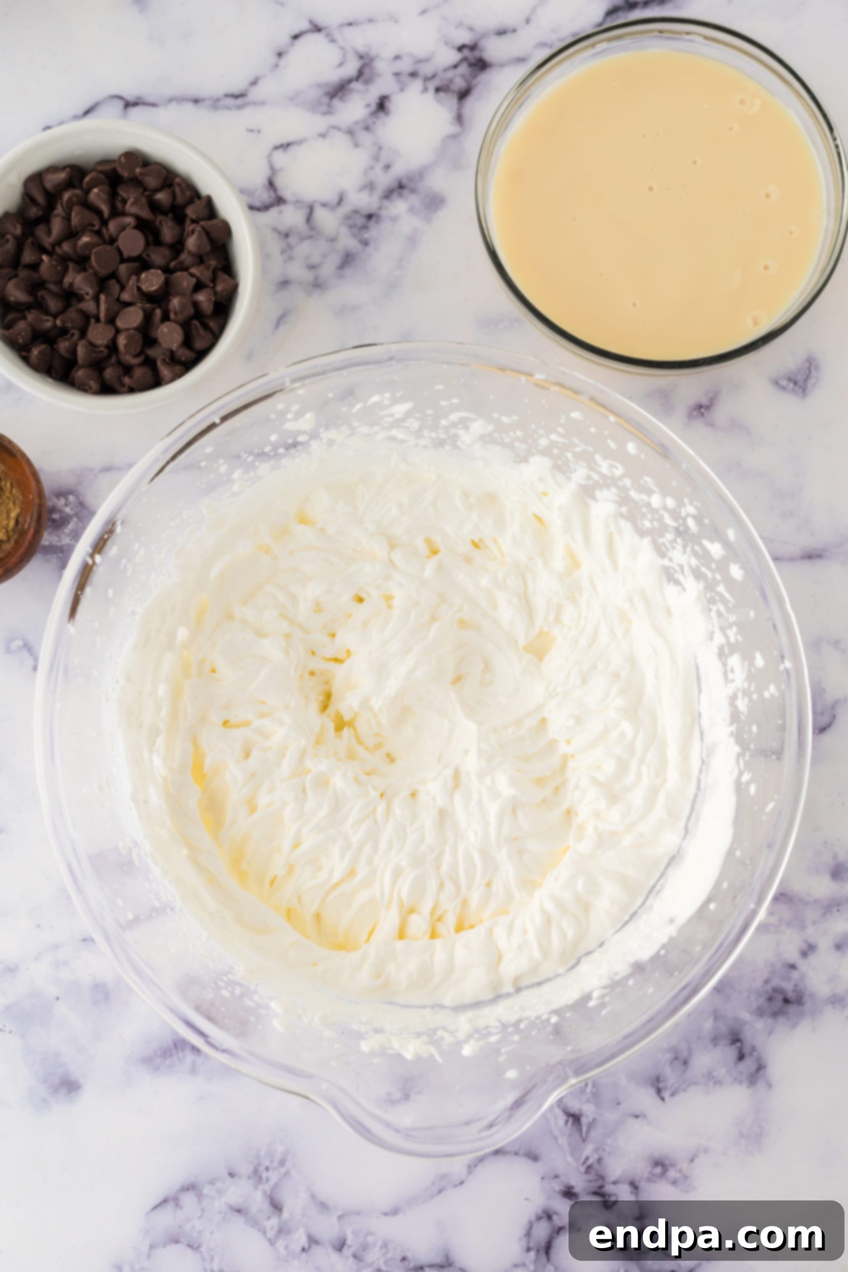Bowl of heavy cream being whipped with an electric hand mixer.