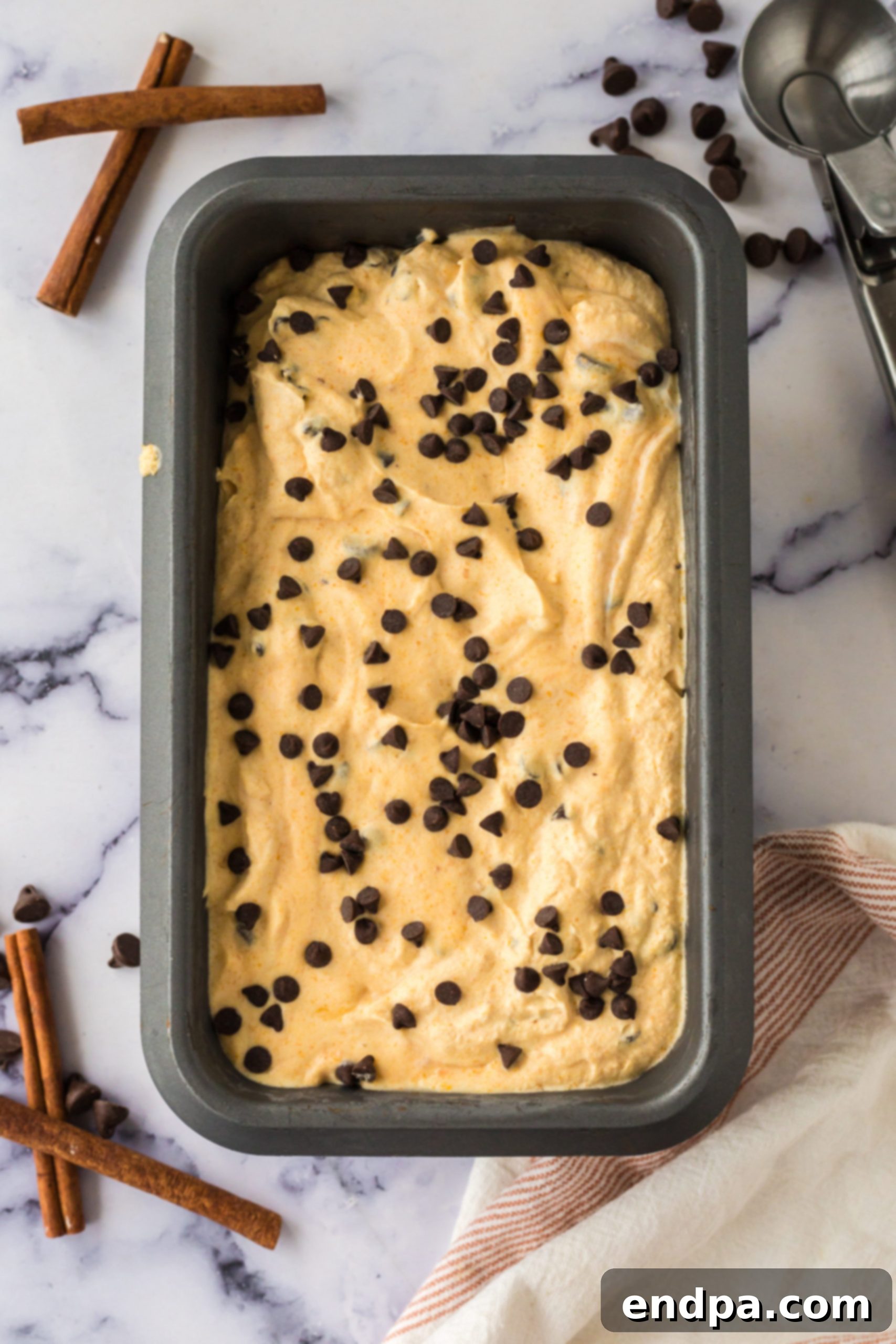 Pumpkin Chocolate Chip Ice Cream mixture spread into a 9x5 inch loaf pan, ready for freezing.