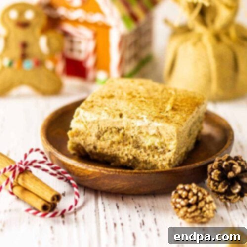 A piece of gingerbread cake on a plate with cinnamon sticks and christmas decorations.