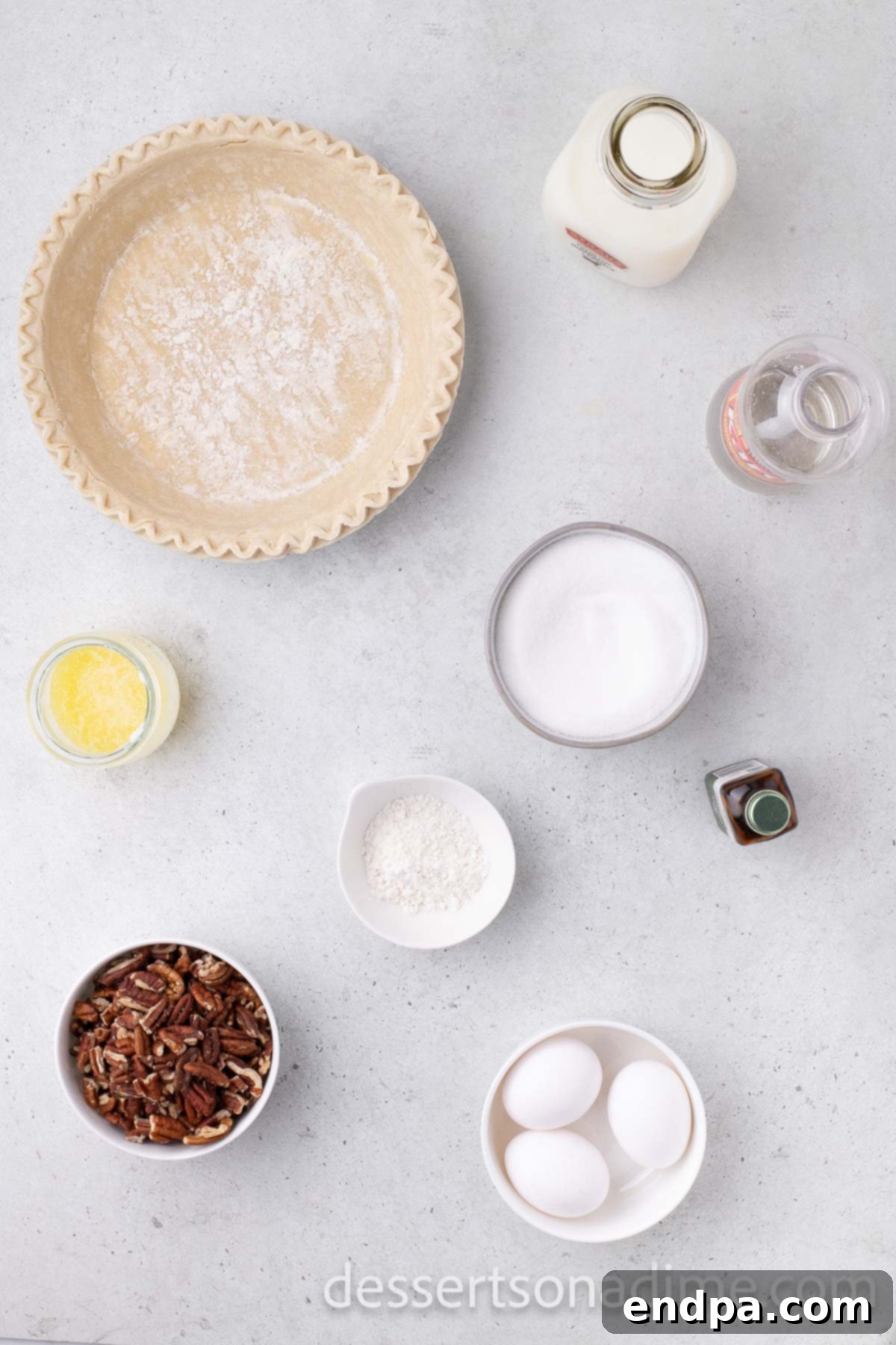 Pecan pie ingredients laid out: pie crust, fresh eggs, light corn syrup, vanilla extract, whole milk, all-purpose flour, melted butter, and pecan halves.