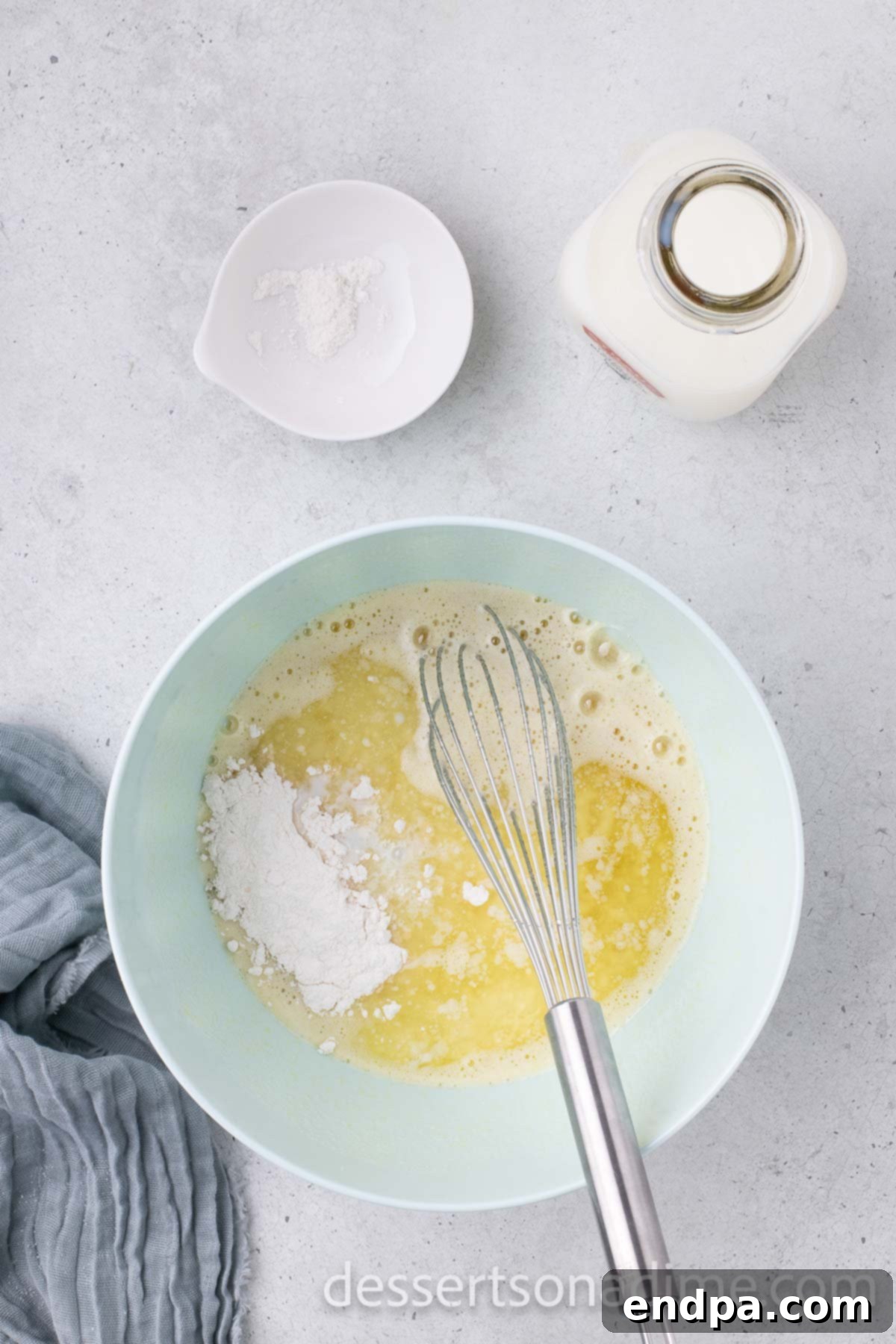 A mixing bowl with granulated sugar, corn syrup, eggs, and vanilla extract being combined.