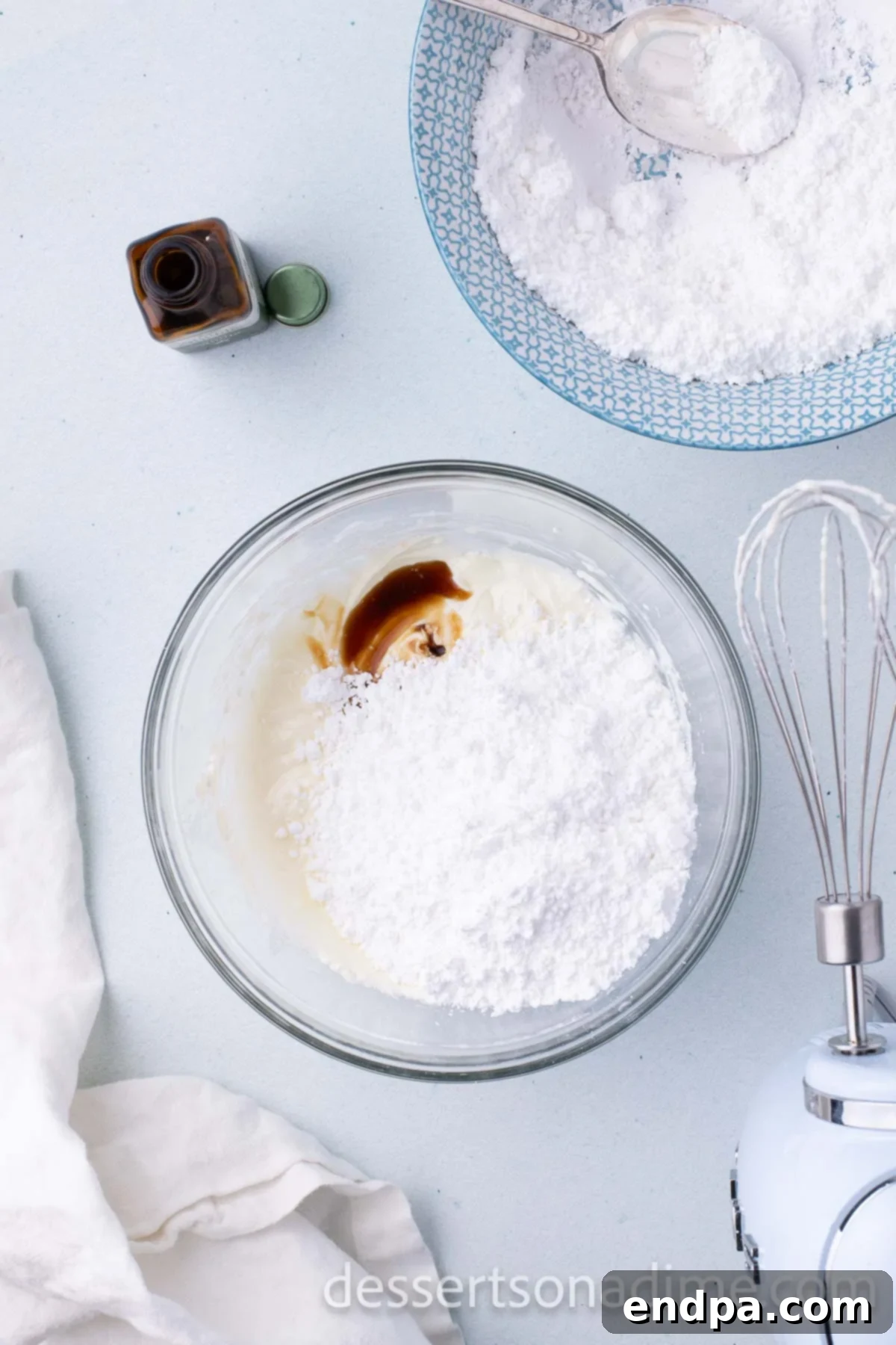 Step 2: Adding vanilla extract and sifted powdered sugar to the creamed mixture in a mixing bowl.