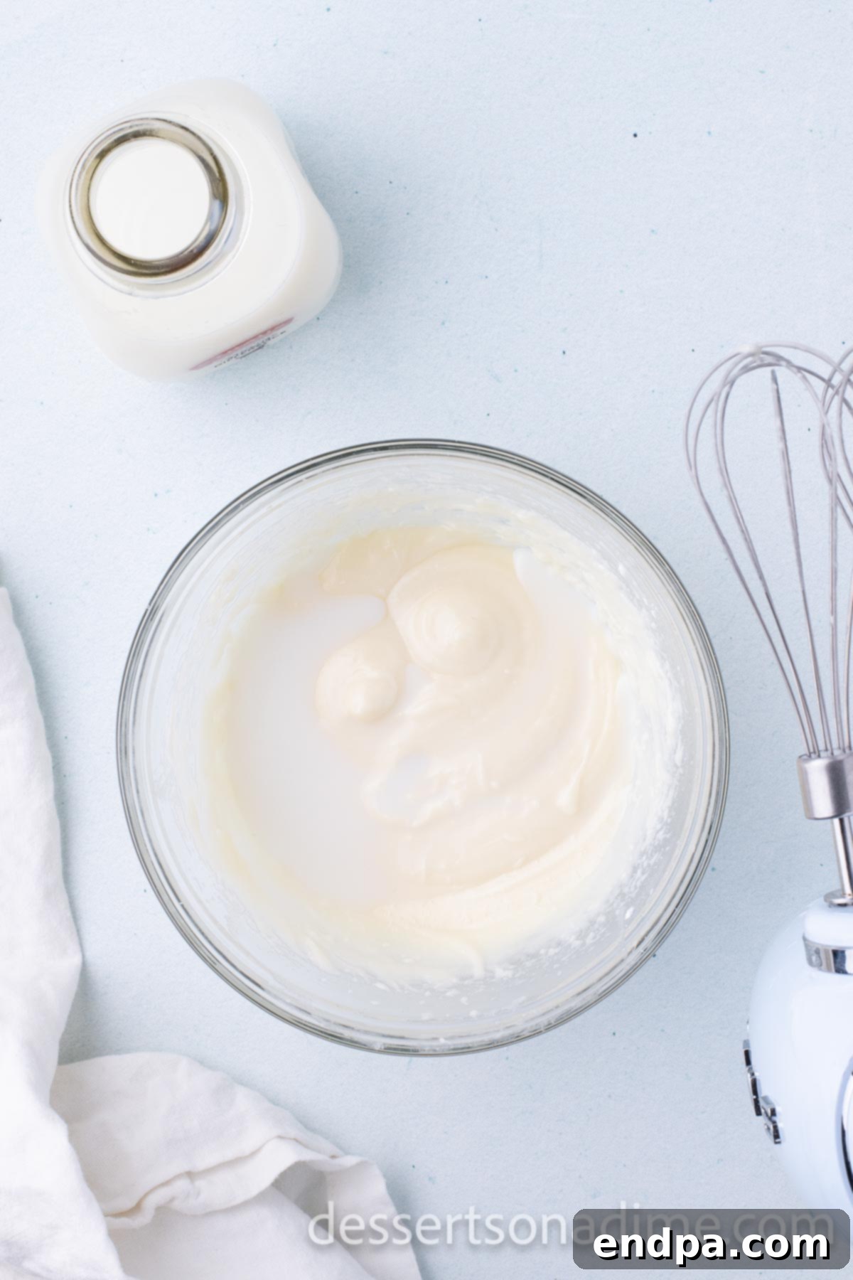 Step 3: Slowly adding milk, one tablespoon at a time, to the cream cheese glaze mixture to achieve the desired consistency.