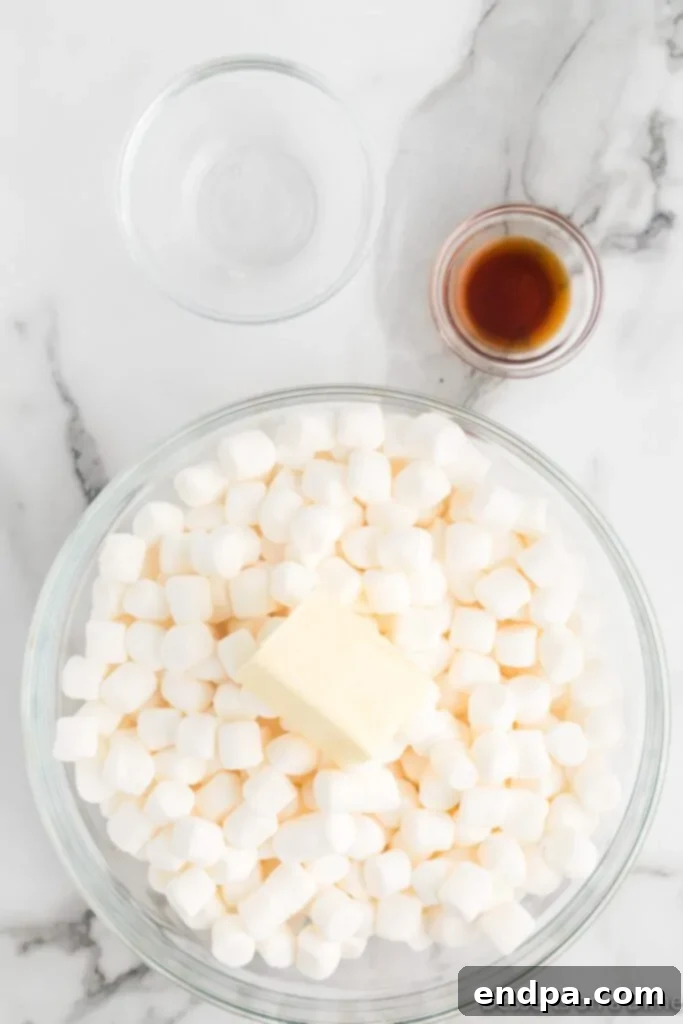 Mini marshmallows and a cube of unsalted butter sitting in a microwave-safe bowl, ready to be melted into a gooey mixture.