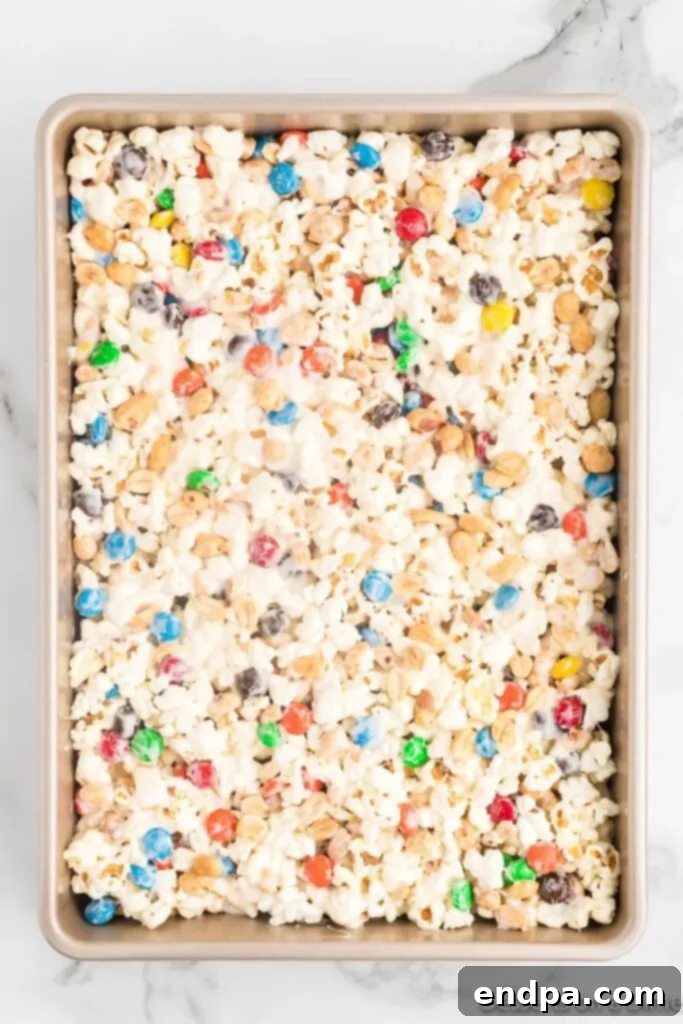 The freshly combined popcorn mixture, pressed into a baking dish and allowed to set, showing its even texture and colorful inclusions.