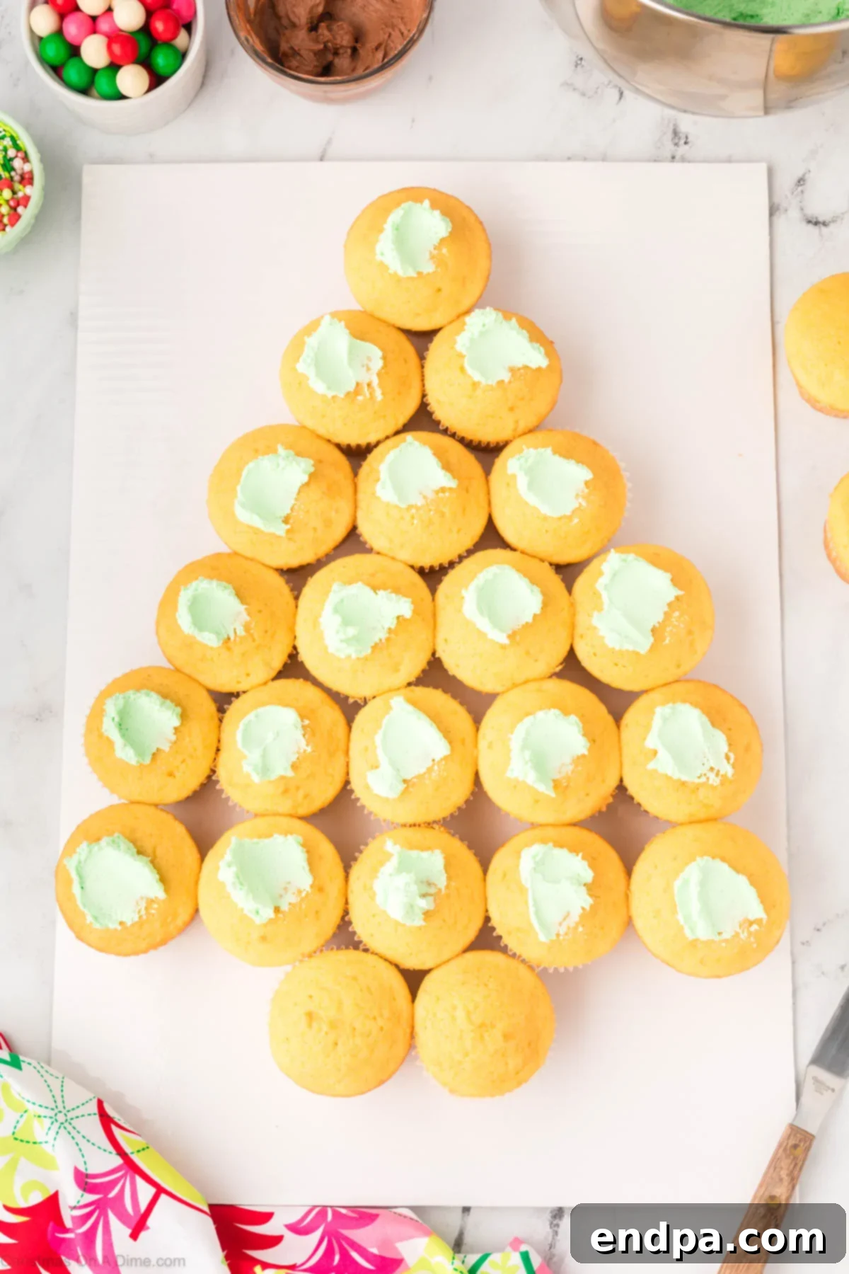 Green frosting dolloped onto each cupcake, forming the base layer for the tree.
